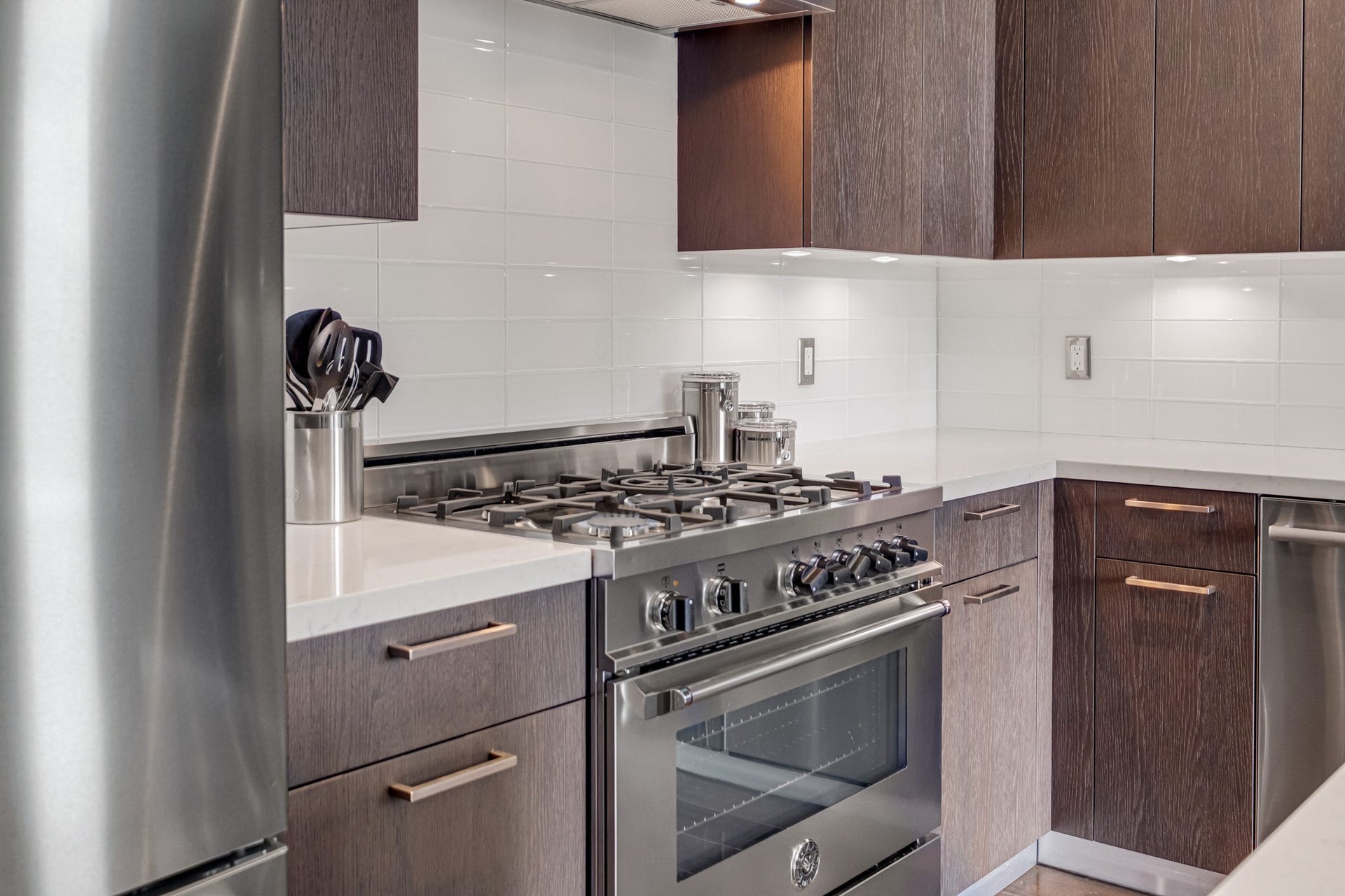 1211 Caroline Street, #1801, Houston, TX 77002 Modern kitchen featuring sleek
stainless steel appliances, dark
wood cabinetry, and a white
glass tile backsplash, highlighted
by an Italian Bertazzoni 6-burner
gas range with vent hood.