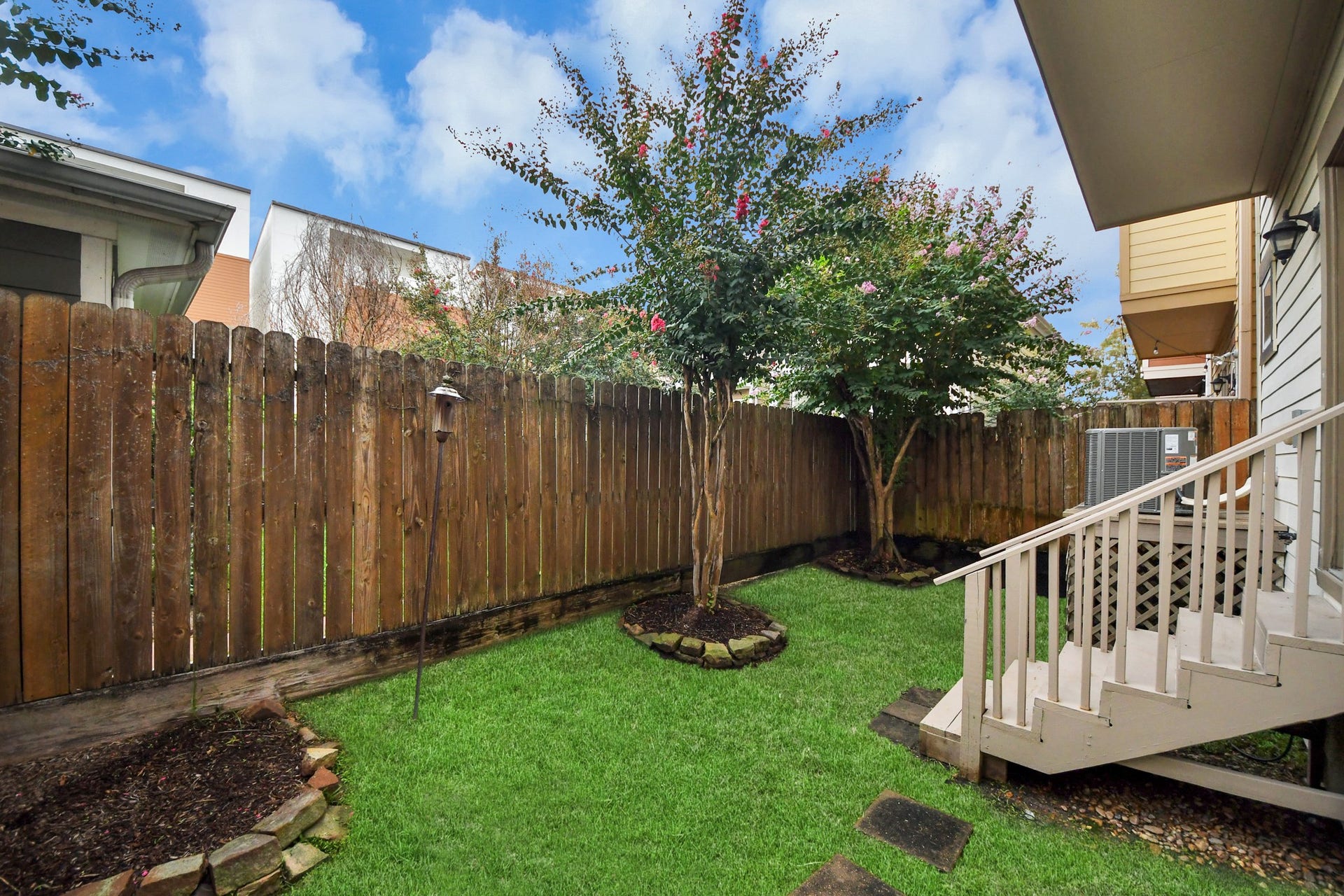 1617 W 23rd Street, Houston, TX 77008 Charming backyard with grass, mature trees, and a cozy wooden fence providing privacy and a space to relax and enjoy the outdoors, in the heart of the city!