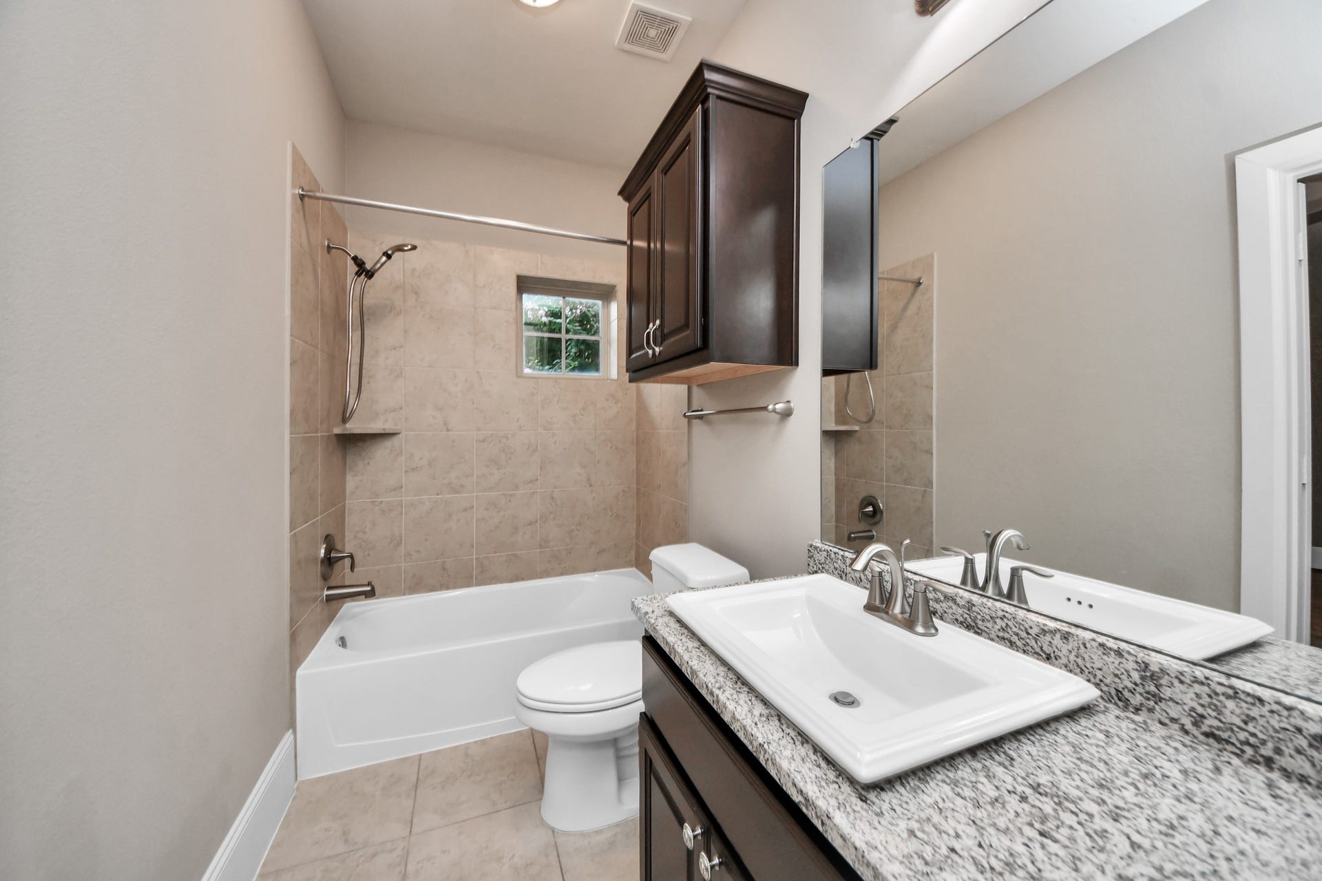 1617 W 23rd Street, Houston, TX 77008 Stylish and convenient, this downstairs en-suite bathroom boasts elegant granite countertops and a shower-tub combo.