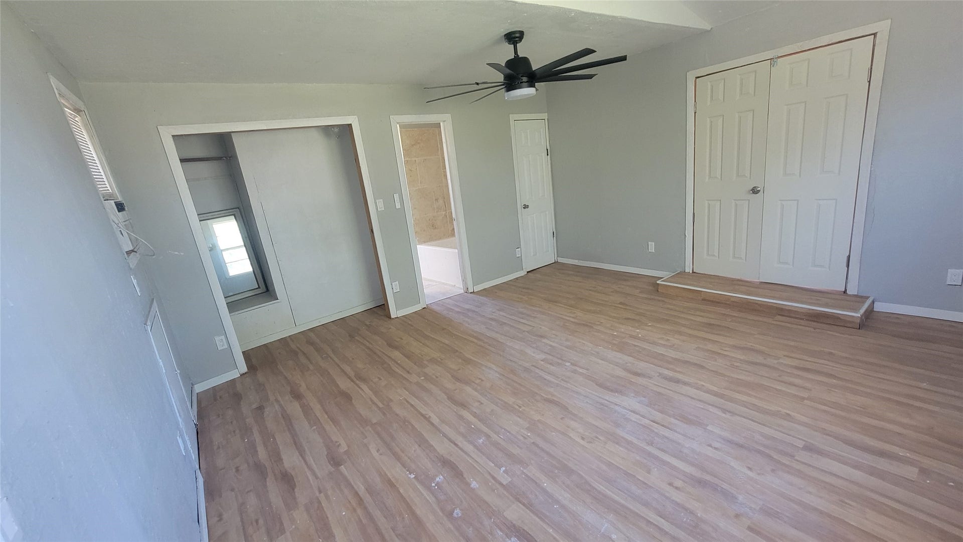 12018 Sandpiper Road, Angleton, TX 77515 This room features light wood flooring, neutral gray walls, and a modern ceiling fan. It includes a small closet, double doors, and an adjacent bathroom. Ample natural light comes from a side window.