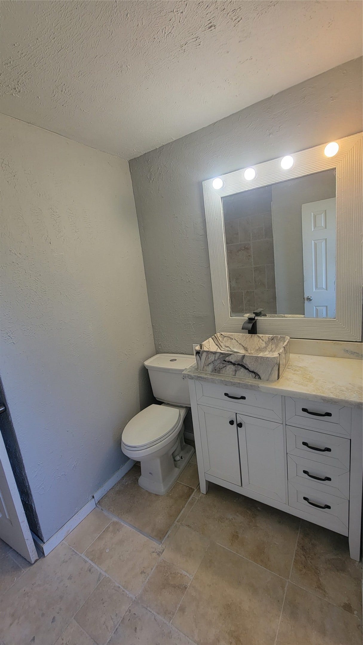 12018 Sandpiper Road, Angleton, TX 77515 This bathroom features a modern vanity with ample storage, a unique vessel sink, and a large mirror with built-in lighting. It has neutral tile flooring and light-colored walls, creating a clean and spacious feel.