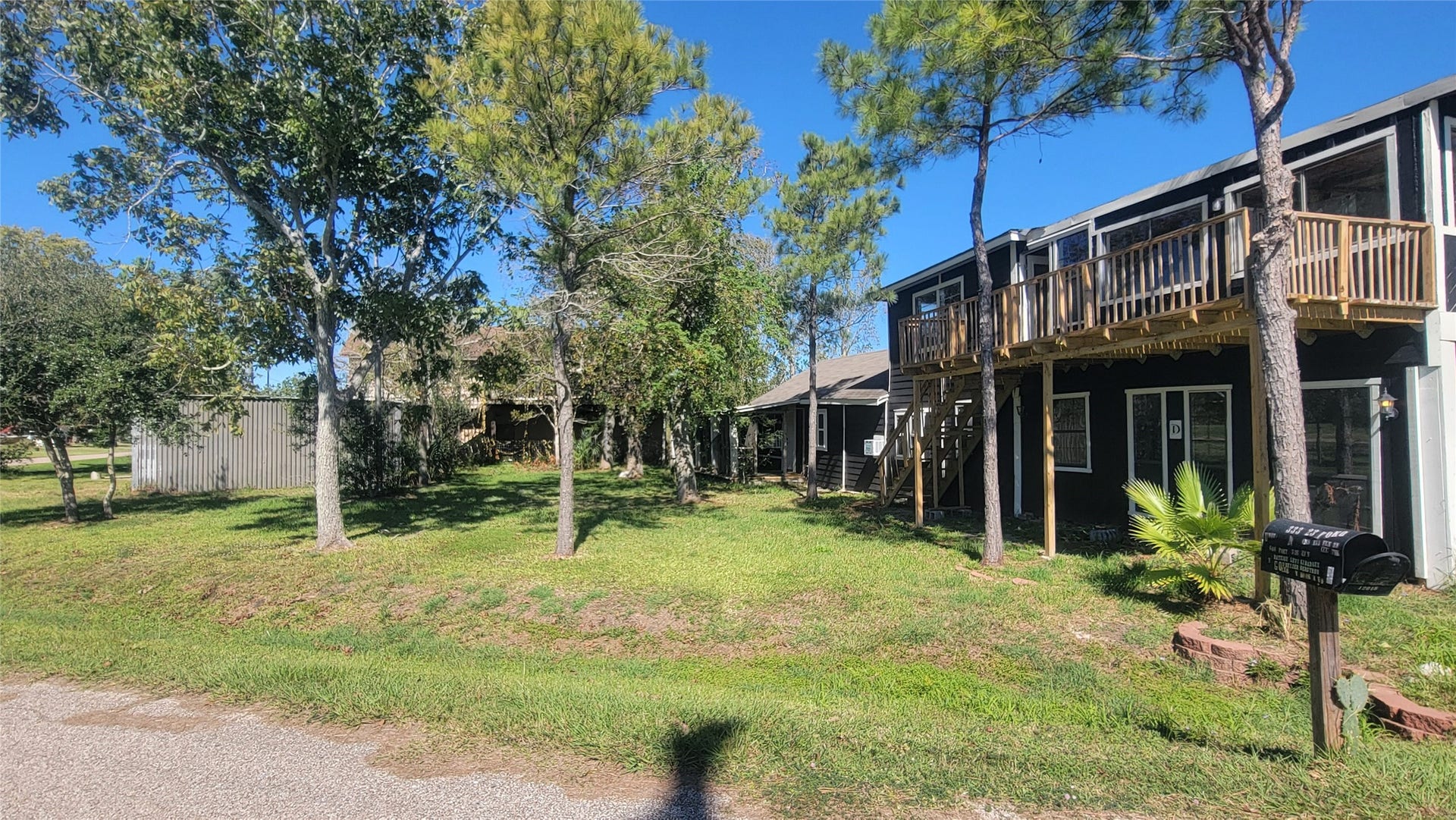 12018 Sandpiper Road, Angleton, TX 77515 Charming two-story home with a wooden balcony, set amidst mature trees. The spacious yard offers plenty of greenery, providing a serene and private outdoor space. The property is located on a quiet street, perfect for peaceful living.