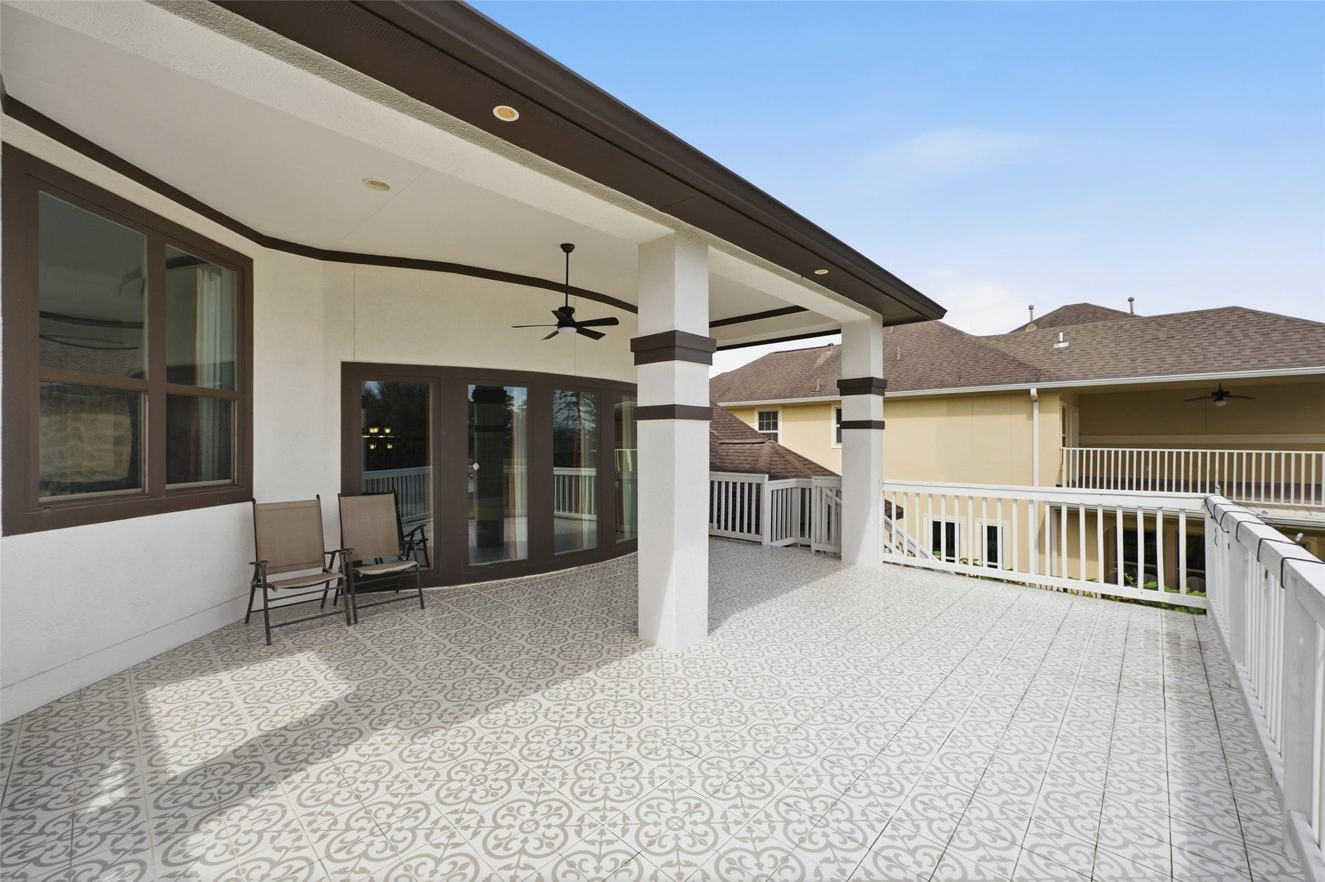 8311 Caroline Ridge Drive, Humble, TX 77396 Expansive covered patio with elegant patterned tiles and ceiling fans, perfect for outdoor relaxation and entertaining.