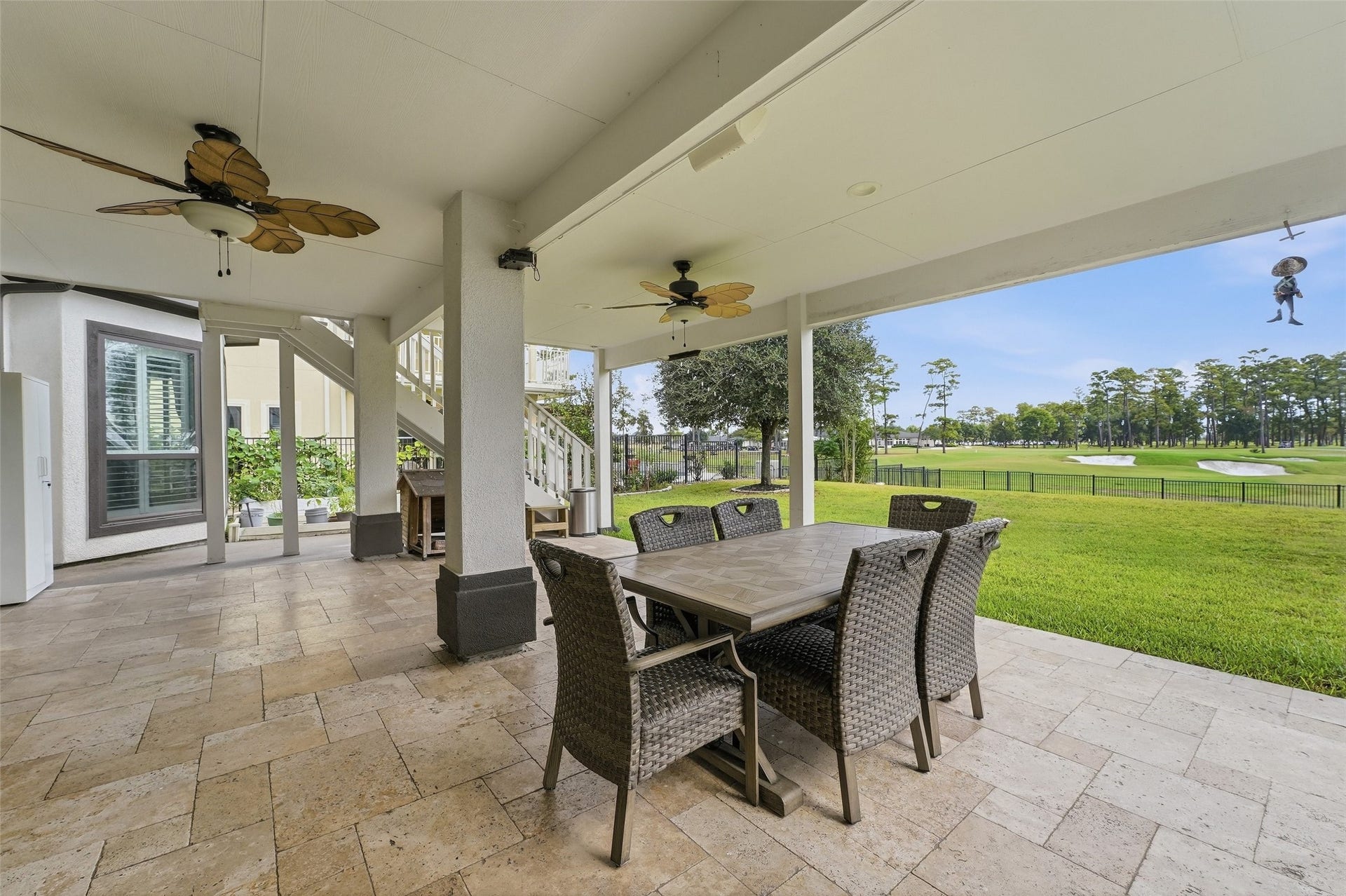 8311 Caroline Ridge Drive, Humble, TX 77396 Spacious covered patio with elegant tile flooring, ceiling fans, and a dining area overlooking a lush green golf course, perfect for outdoor entertaining.