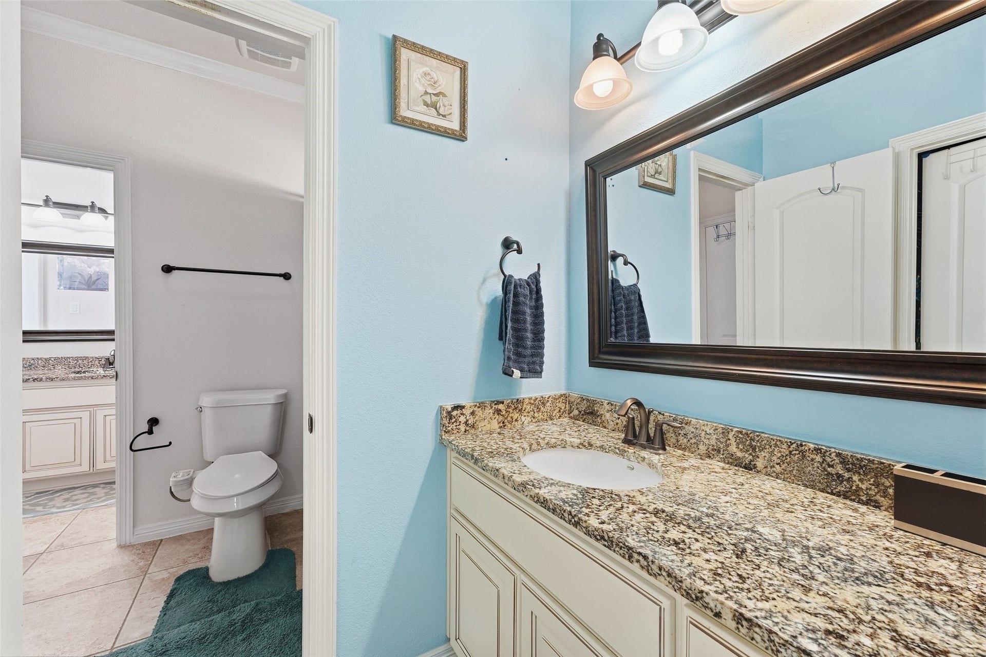 8311 Caroline Ridge Drive, Humble, TX 77396 Bright bathroom featuring a granite countertop, large mirror, and stylish lighting, with easy access to the adjacent room.