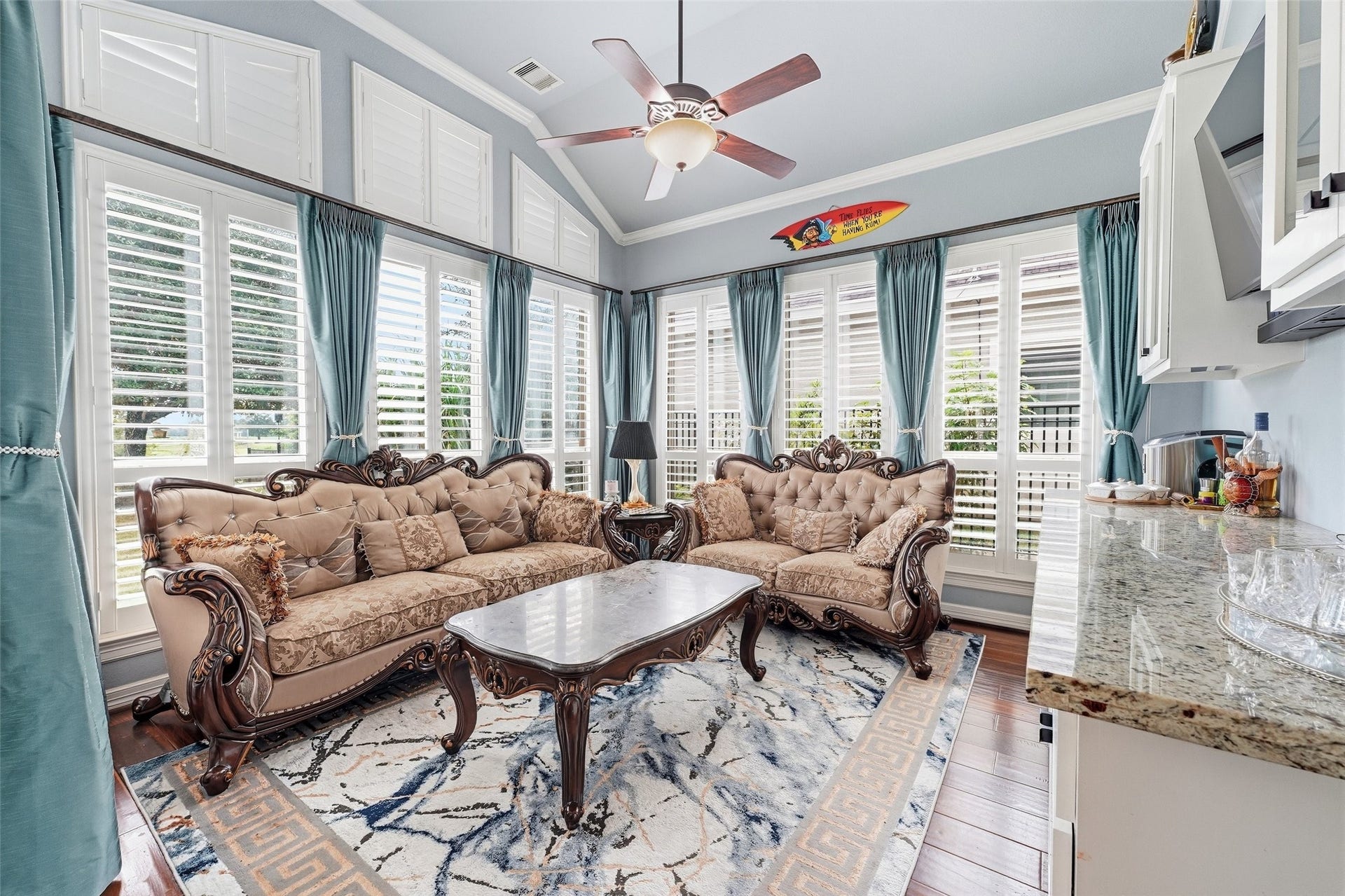 8311 Caroline Ridge Drive, Humble, TX 77396 Elegant living space with high ceilings, abundant natural light, and classic furnishings. Large windows with shutters and draped curtains create a bright and inviting atmosphere.