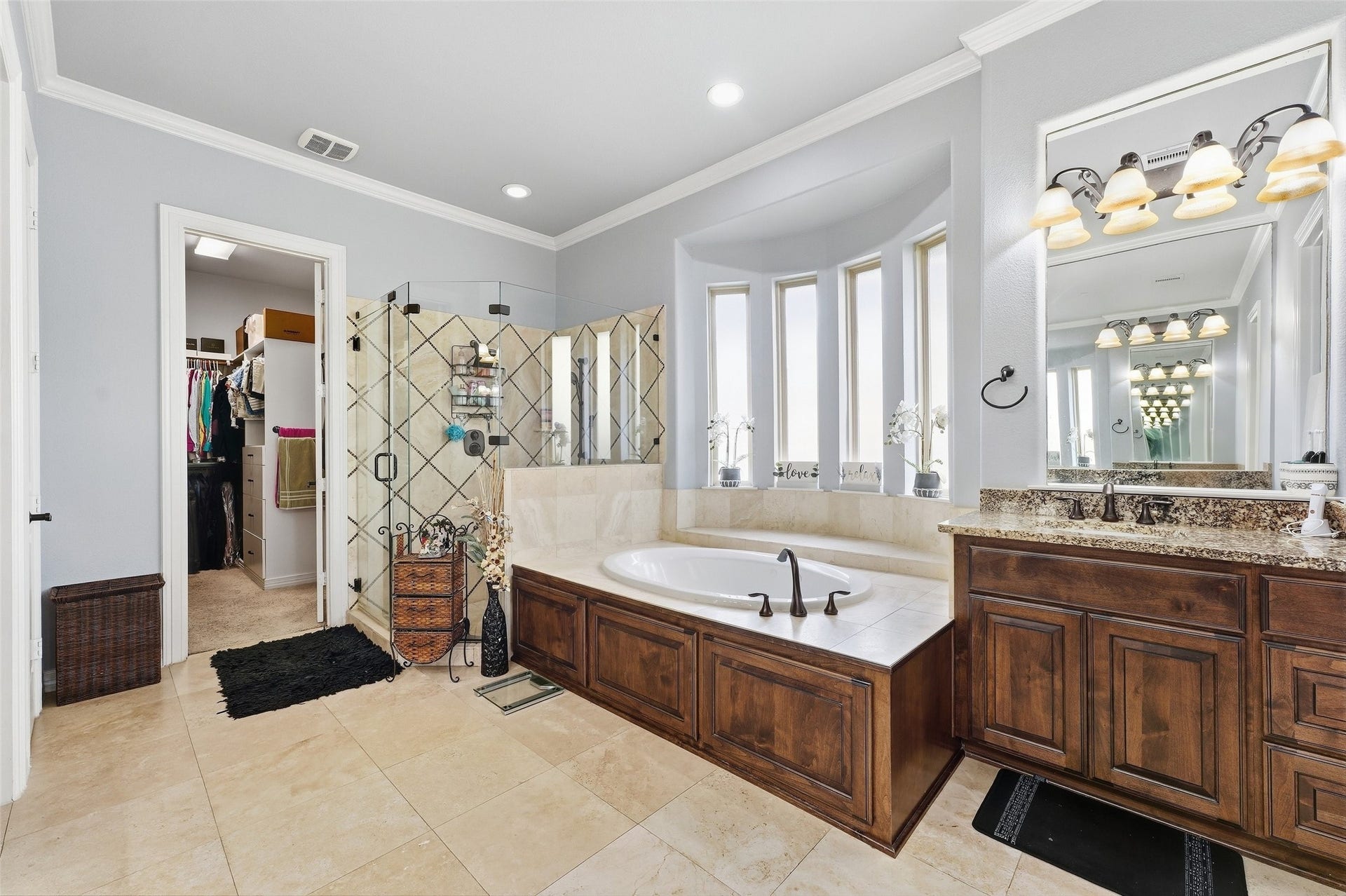 8311 Caroline Ridge Drive, Humble, TX 77396 Luxurious bathroom featuring a spacious soaking tub, elegant granite countertops, and a glass-enclosed shower, with direct access to a walk-in closet.