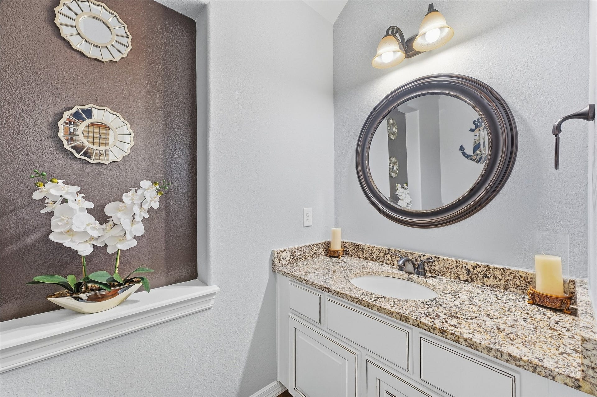 8311 Caroline Ridge Drive, Humble, TX 77396 Elegant bathroom with a granite countertop, and a stylish round mirror complemented by soft lighting.
