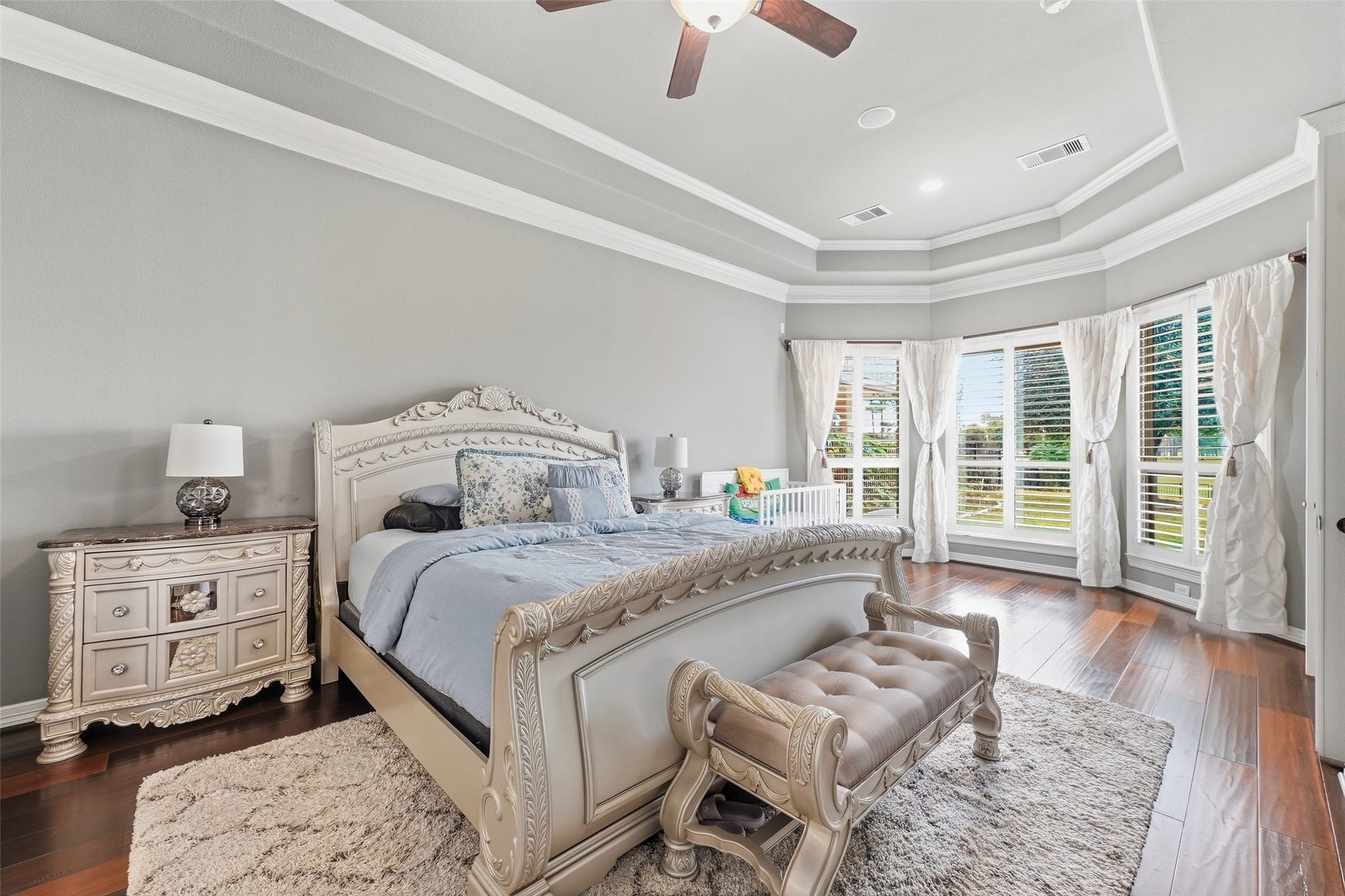8311 Caroline Ridge Drive, Humble, TX 77396 Elegant master bedroom featuring a luxurious tray ceiling, rich wood floors, and abundant natural light from expansive bay windows.