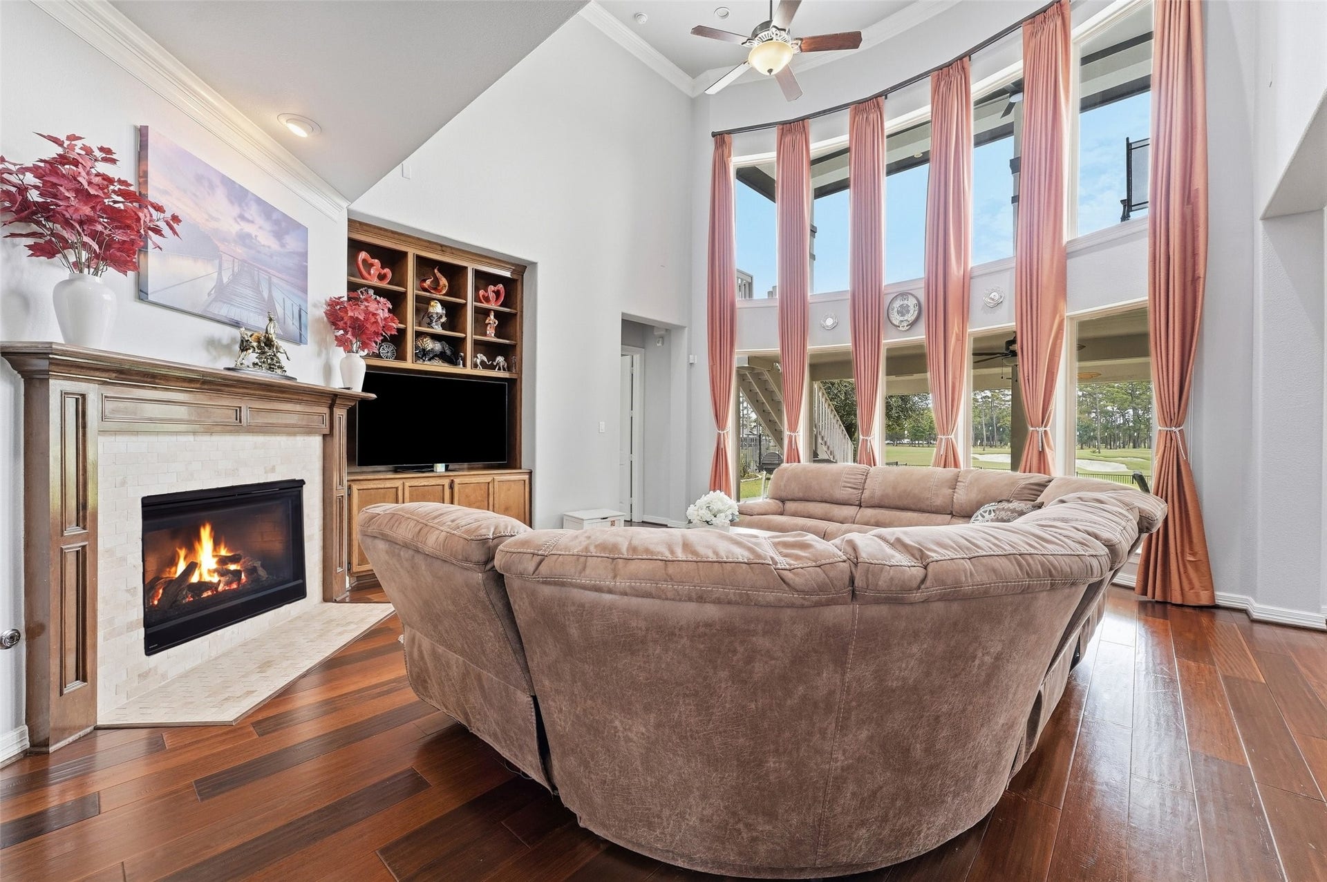 8311 Caroline Ridge Drive, Humble, TX 77396 Spacious living room with a cozy fireplace, elegant built-in shelving, and expansive windows offering abundant natural light and scenic views.