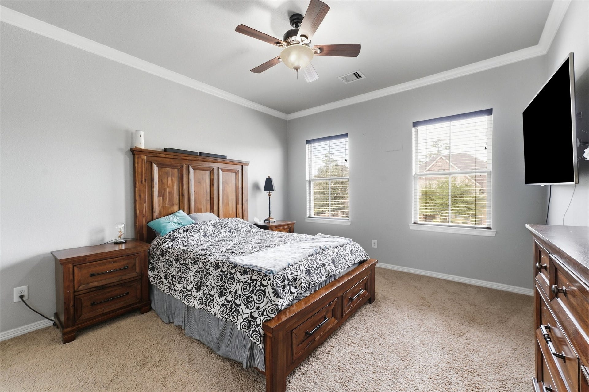 8311 Caroline Ridge Drive, Humble, TX 77396 Spacious bedroom with soft carpet flooring and bright natural light filters through two large windows, creating an inviting and cozy atmosphere.