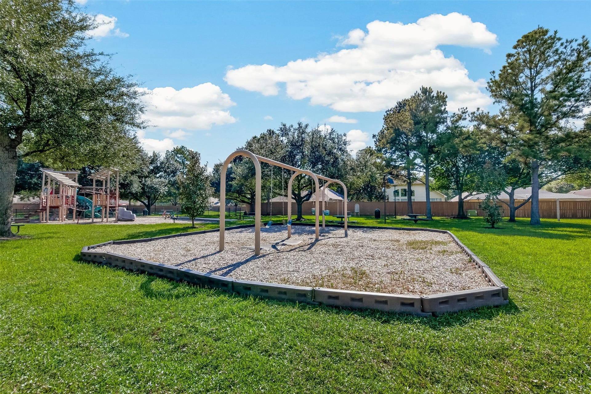 18019 Rexine Lane, Cypress, TX 77433 Charming community playground set amidst lush greenery, featuring swings and a play structure, perfect for family enjoyment and outdoor activities.