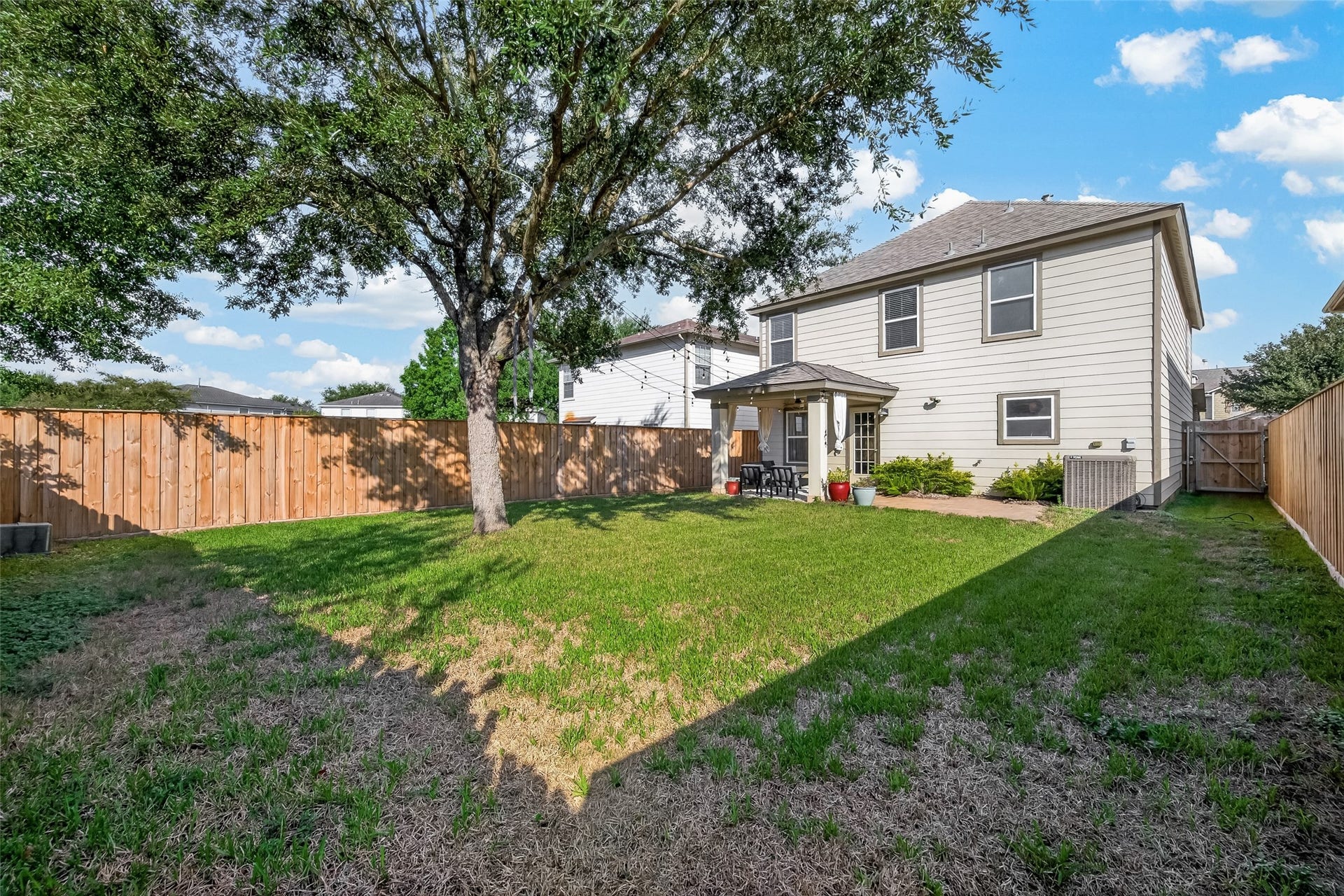 18019 Rexine Lane, Cypress, TX 77433 Charming backyard with a spacious lawn and mature tree, perfect for outdoor activities. The covered patio offers a cozy spot for relaxation and entertainment.