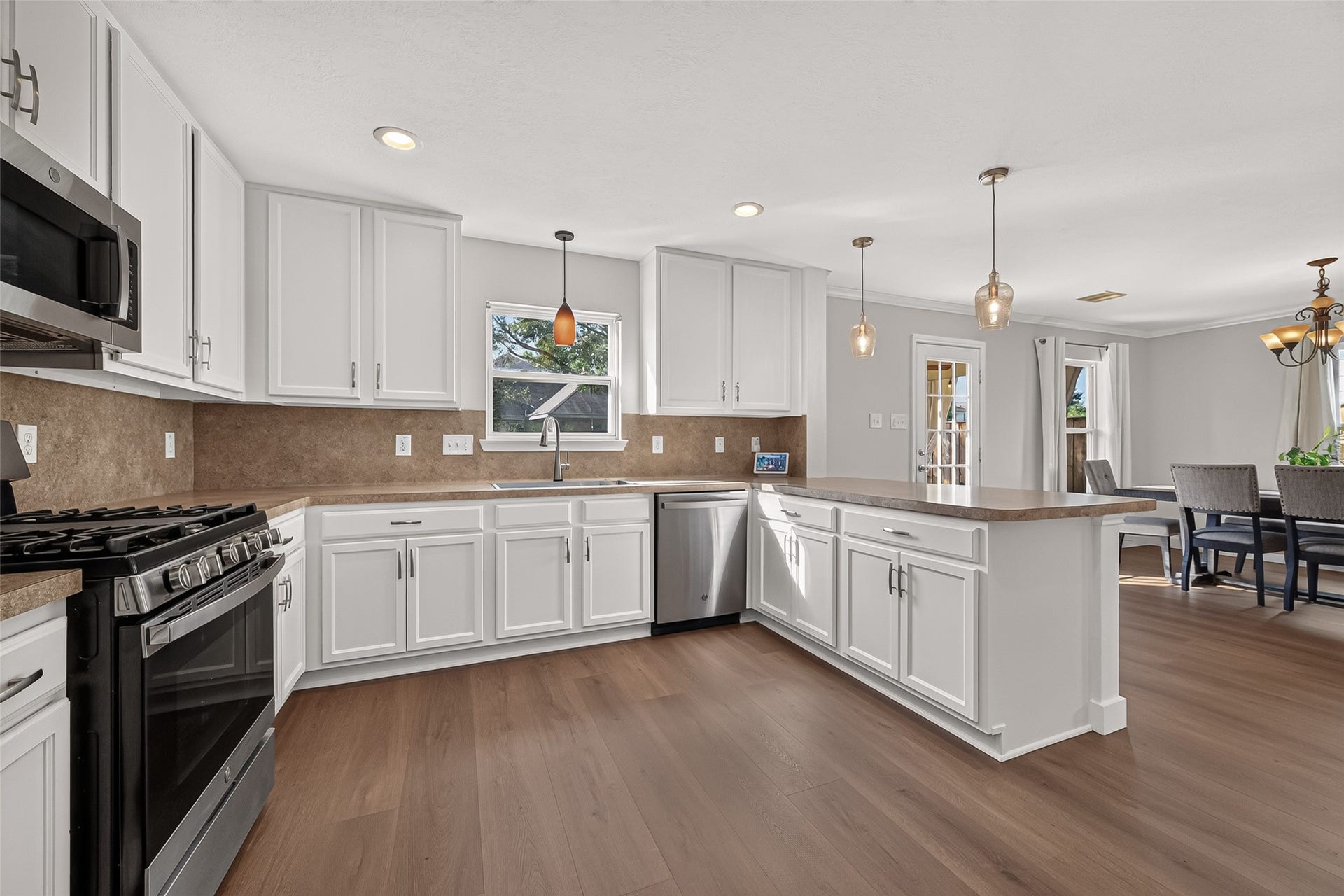 18019 Rexine Lane, Cypress, TX 77433 Spacious kitchen with sleek white cabinetry, stainless steel appliances, and a large island, seamlessly connecting to a bright dining area.