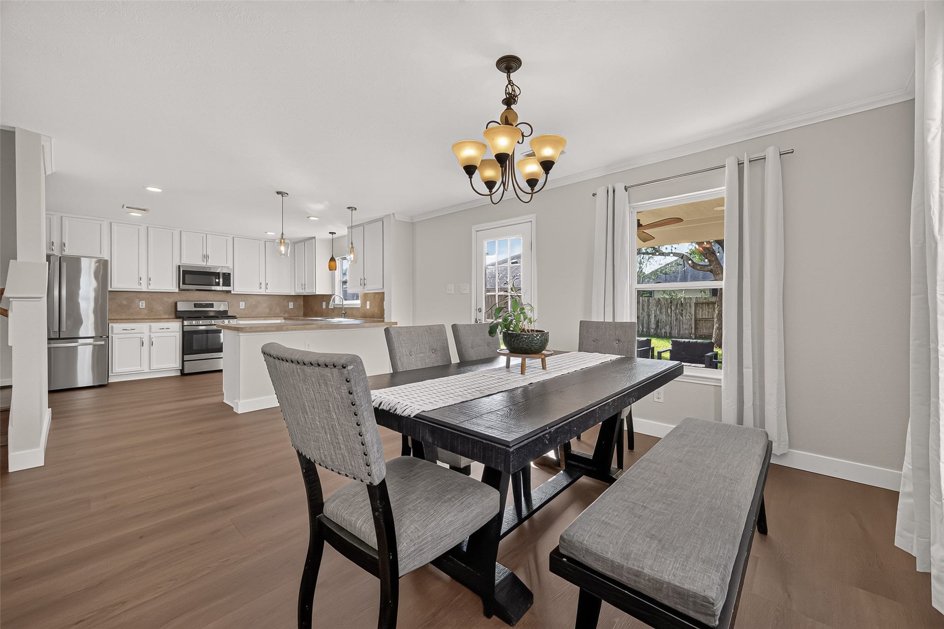 18019 Rexine Lane, Cypress, TX 77433 Bright and inviting dining area with elegant lighting, seamlessly connected to a modern kitchen featuring stainless steel appliances and ample cabinetry.