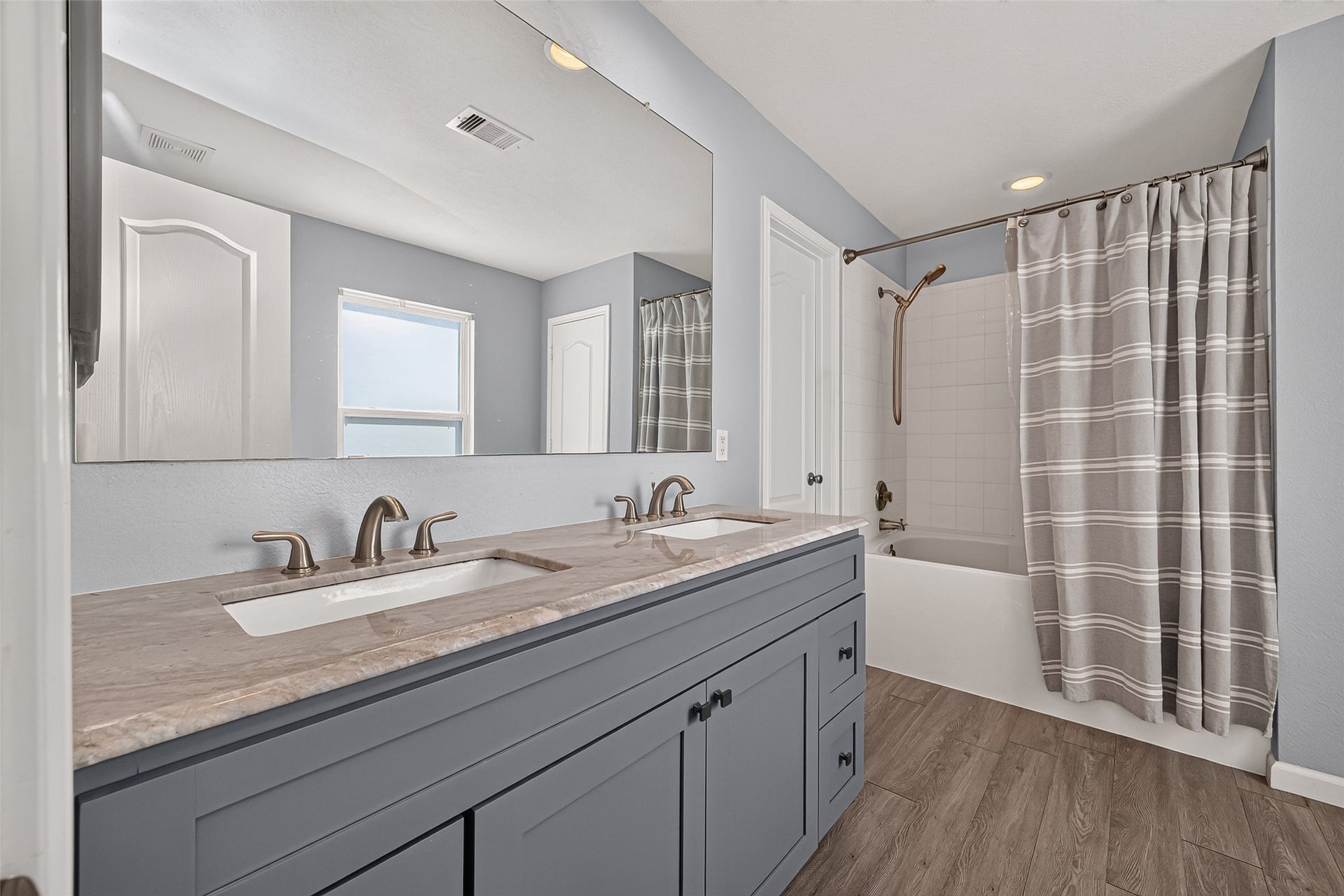 18019 Rexine Lane, Cypress, TX 77433 Stylish bathroom featuring a double vanity with sleek fixtures, a spacious mirror, and a shower-tub combo with a chic curtain.