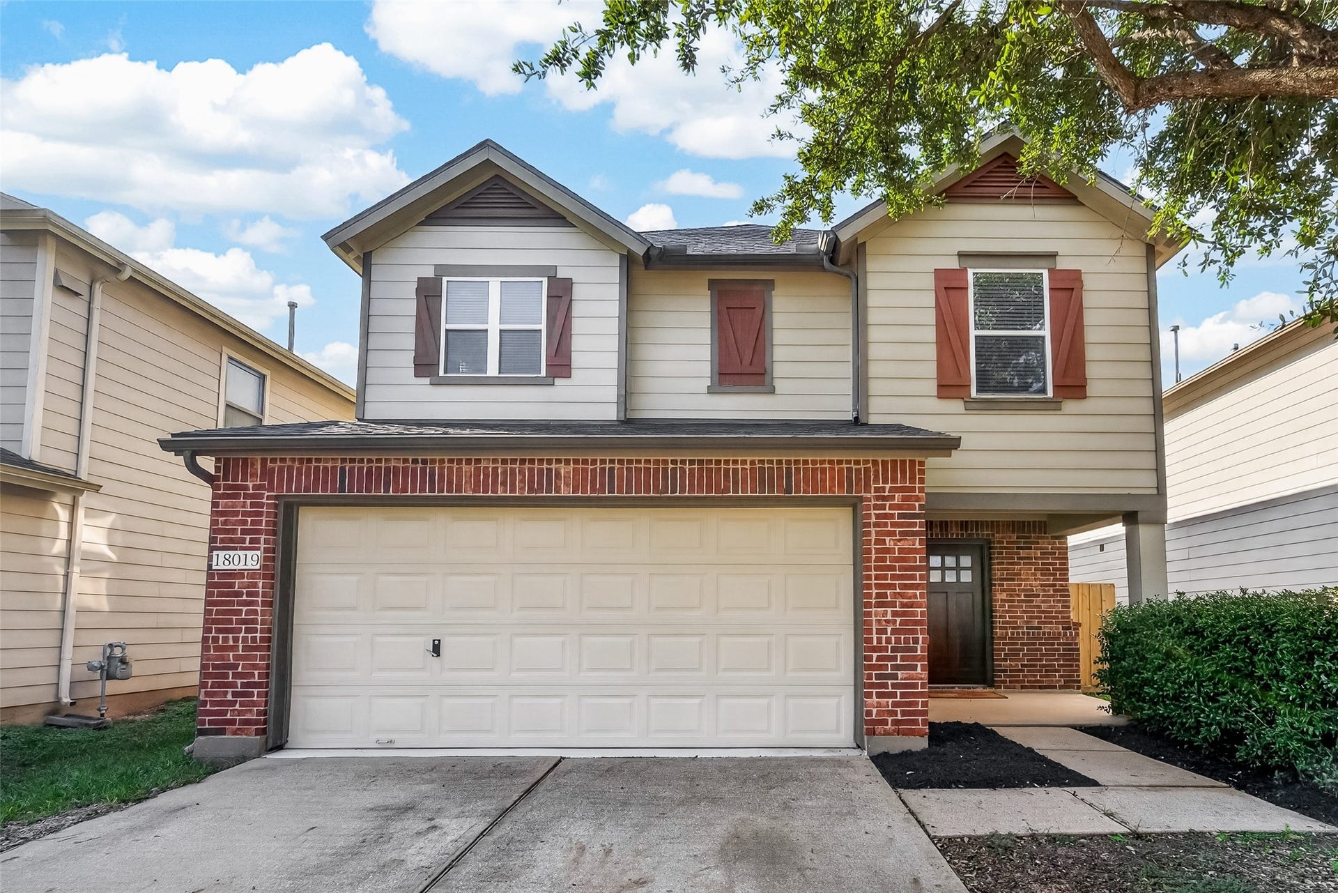 18019 Rexine Lane, Cypress, TX 77433 Charming two-story home with a classic brick facade and welcoming shutters, featuring a spacious two-car garage and a cozy front entrance nestled under mature trees.