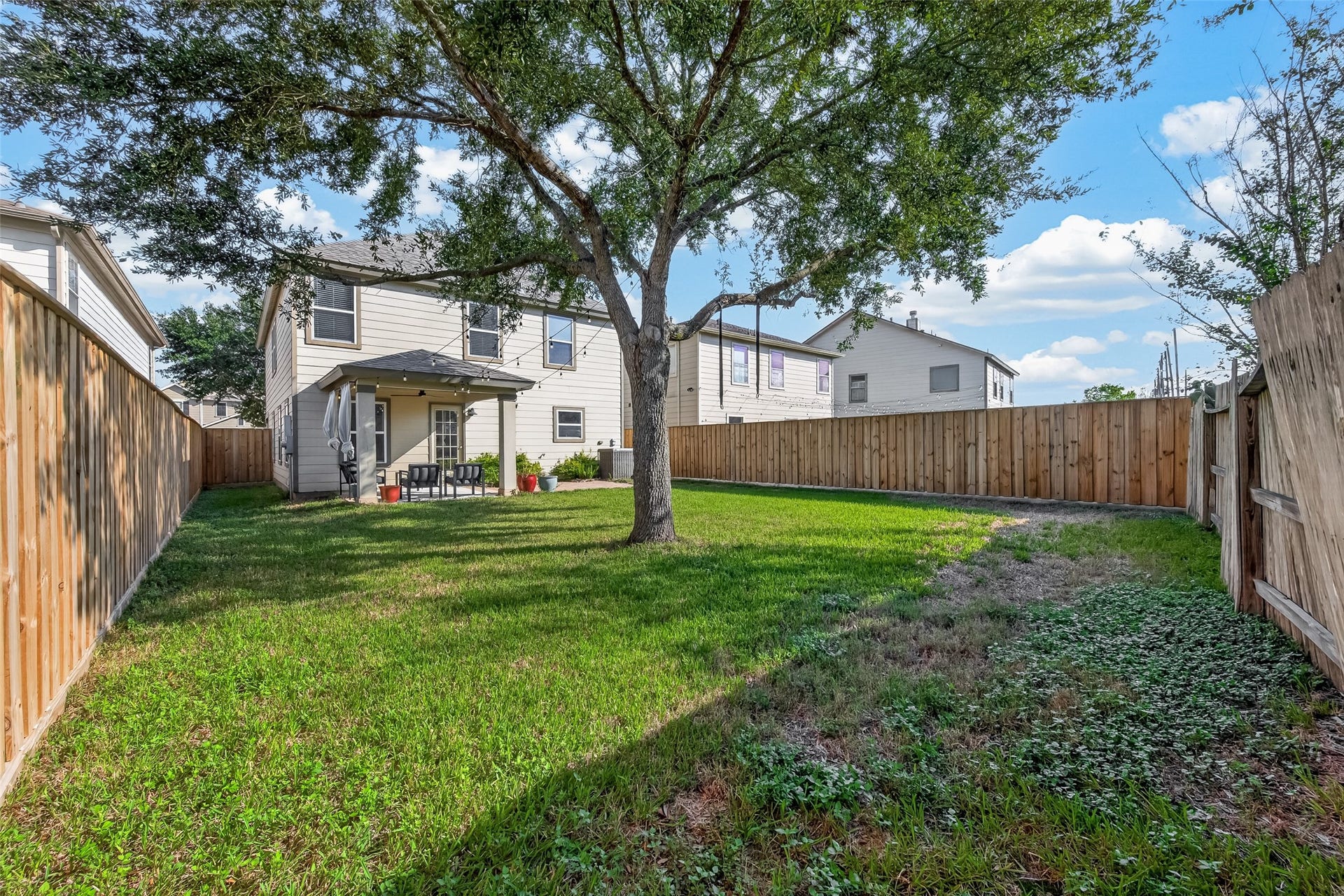 18019 Rexine Lane, Cypress, TX 77433 Spacious fenced backyard with a lush lawn, mature tree, and a covered patio perfect for outdoor relaxation.