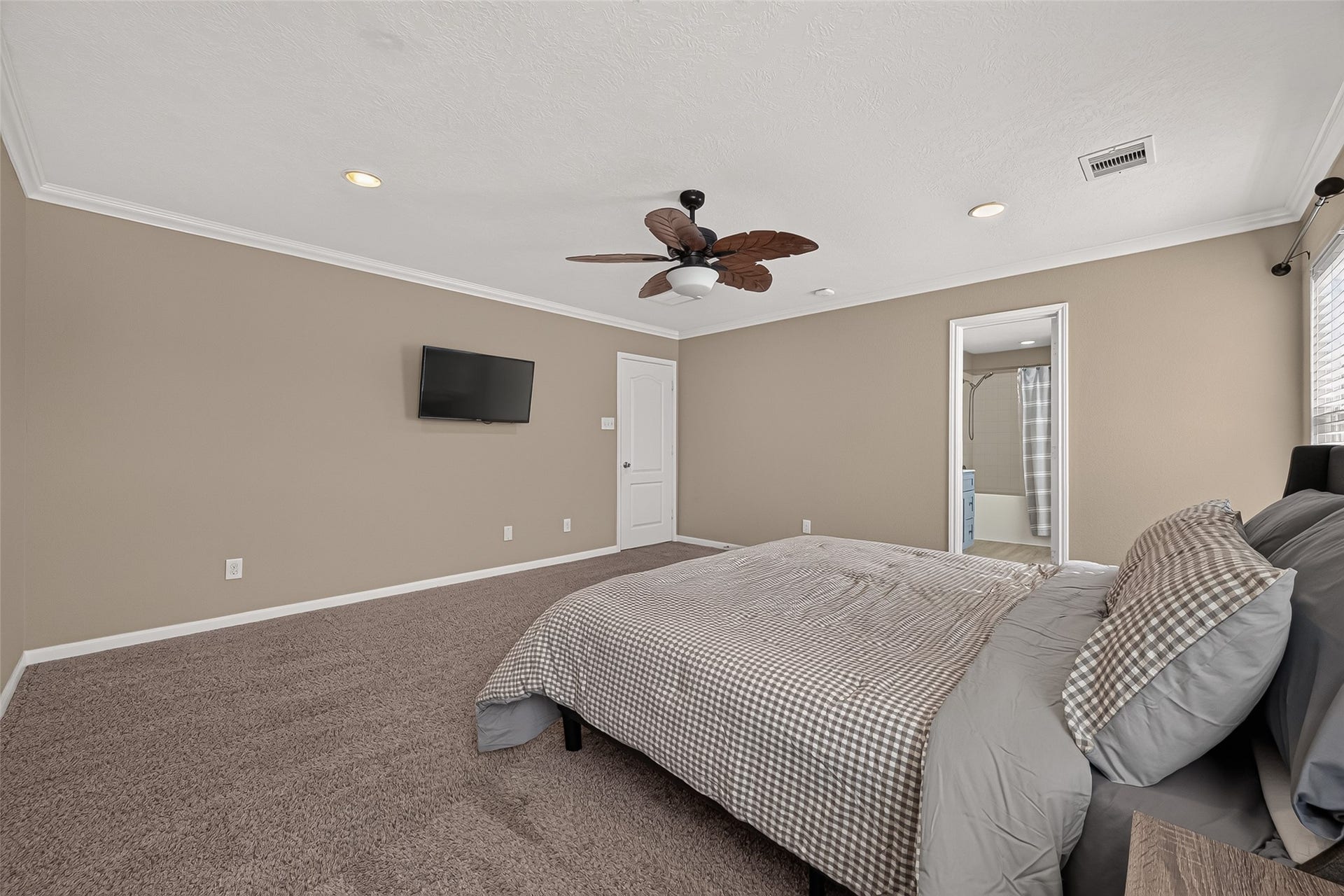 18019 Rexine Lane, Cypress, TX 77433 Spacious primary bedroom featuring cozy carpeting, a ceiling fan, and an ensuite bathroom, offering comfort and convenience.