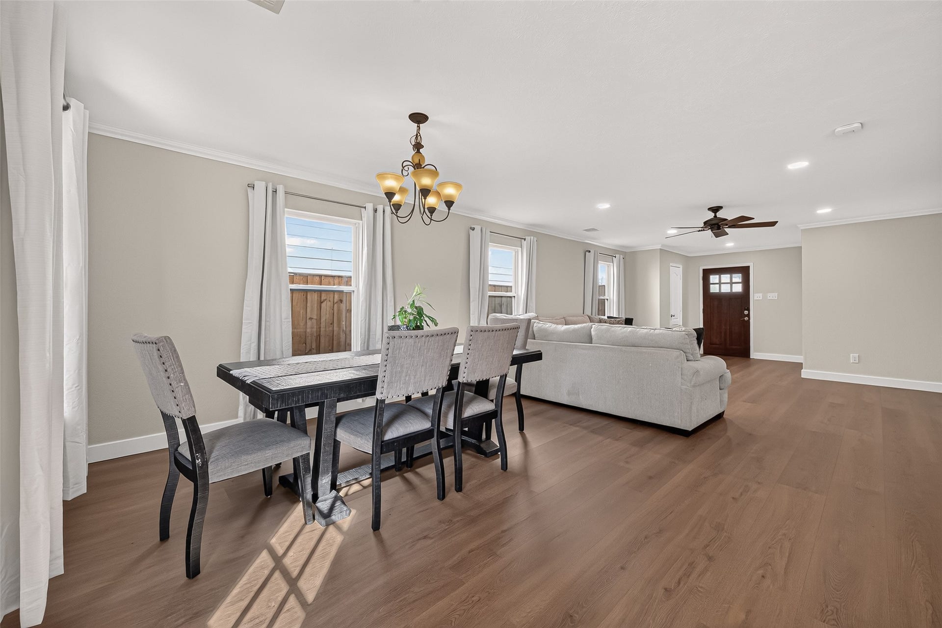 18019 Rexine Lane, Cypress, TX 77433 Spacious and inviting open-plan living and dining area featuring elegant vinyl plank floors, abundant natural light from multiple windows, and a stylish chandelier over the dining space.