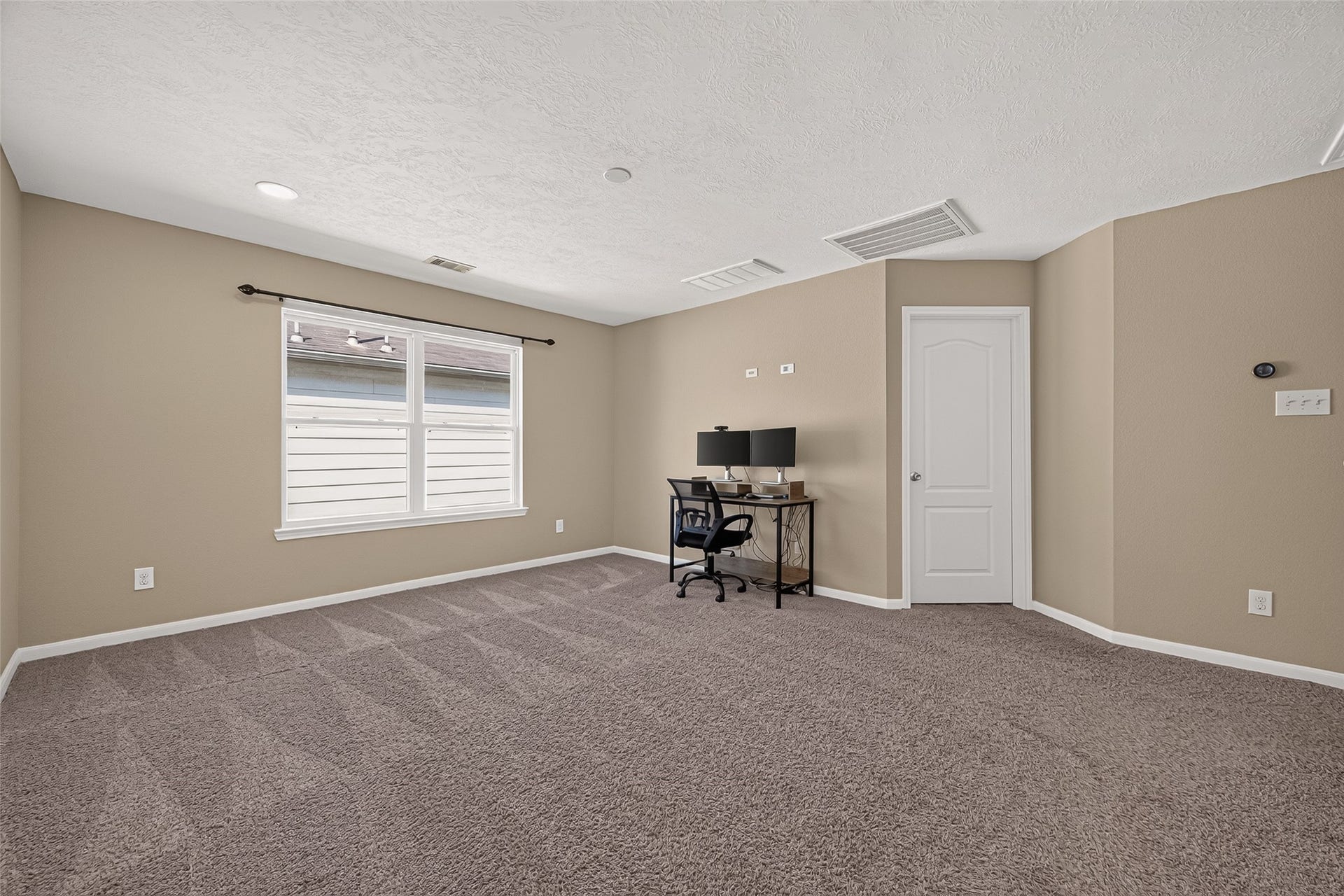 18019 Rexine Lane, Cypress, TX 77433 Spacious game room with neutral walls and plush carpet, featuring a large window for natural light and a cozy workspace nook.