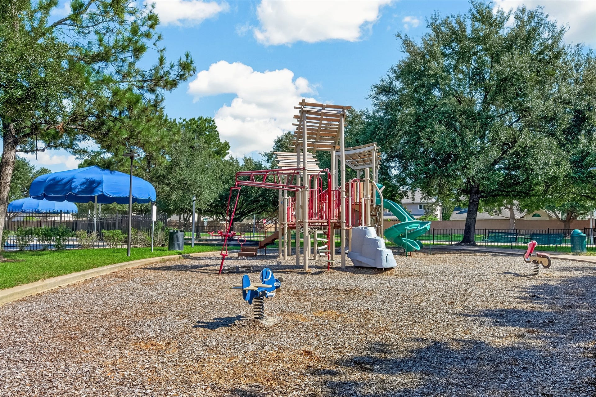 18019 Rexine Lane, Cypress, TX 77433 Charming community playground with modern play structures, surrounded by lush trees and a nearby pool, perfect for family fun and outdoor activities.