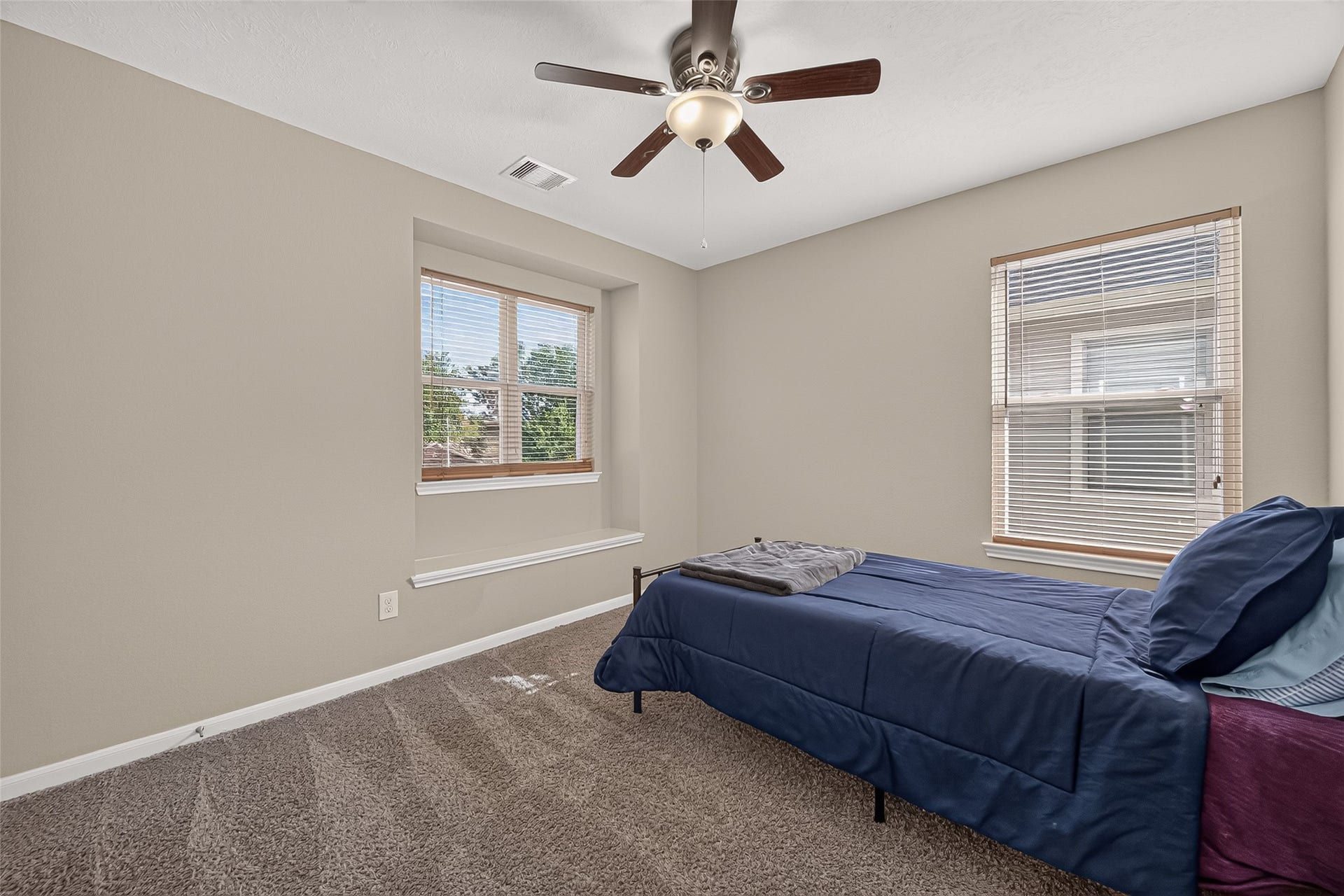 18019 Rexine Lane, Cypress, TX 77433 Cozy secondary bedroom featuring neutral walls, plush carpet, a ceiling fan, and ample natural light from two windows.