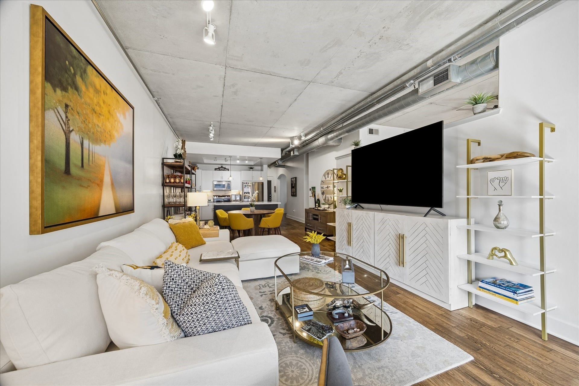 Truly open-concept all the way through.  The living room features a cozy sectional sofa, modern decor, and a sleek entertainment center, seamlessly flowing into a contemporary kitchen and dining area.
