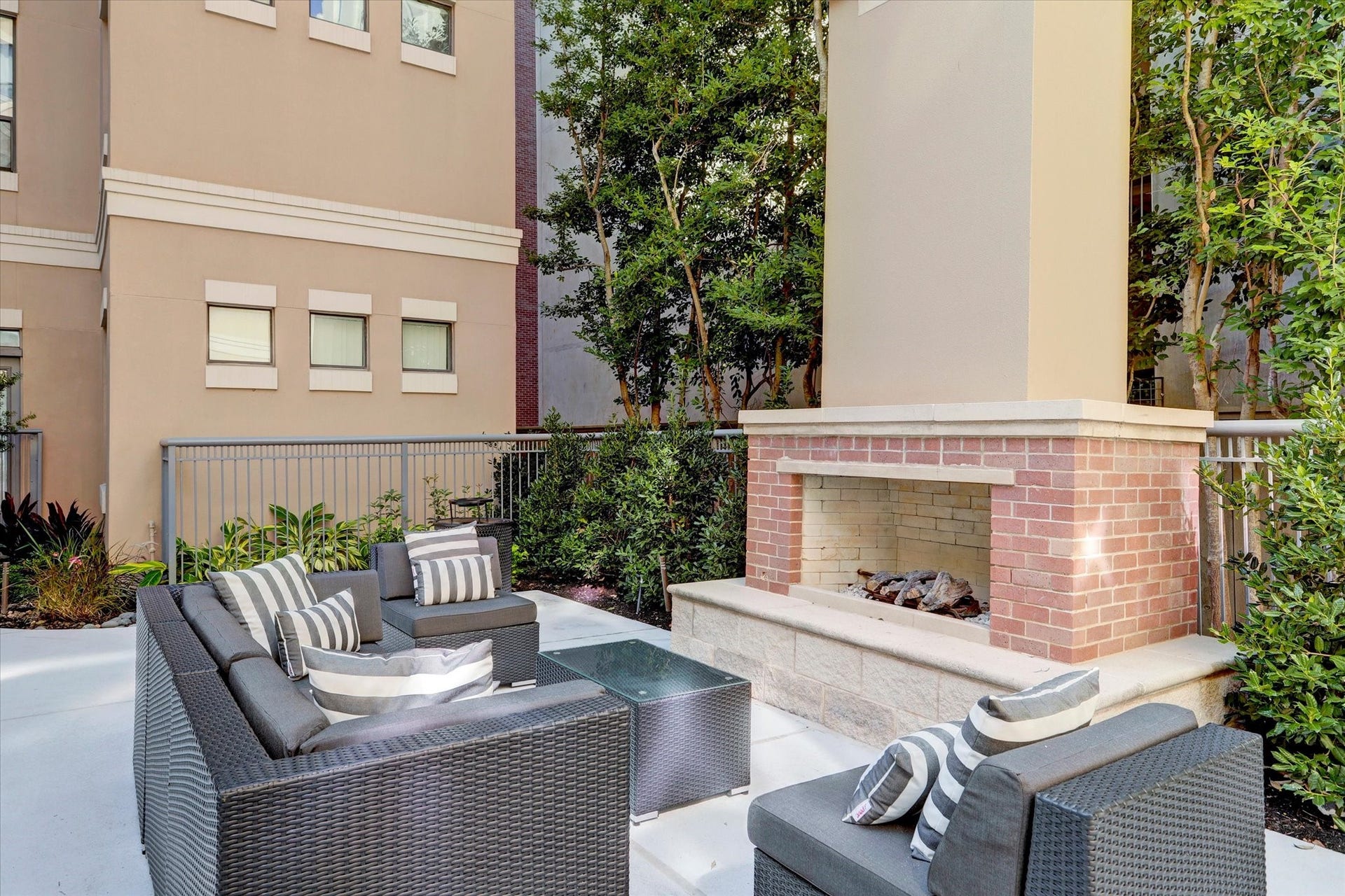 One of the many outdoor living spaces featuring a cozy brick fireplace and stylish seating, perfect for entertaining or just hanging out by the fire.