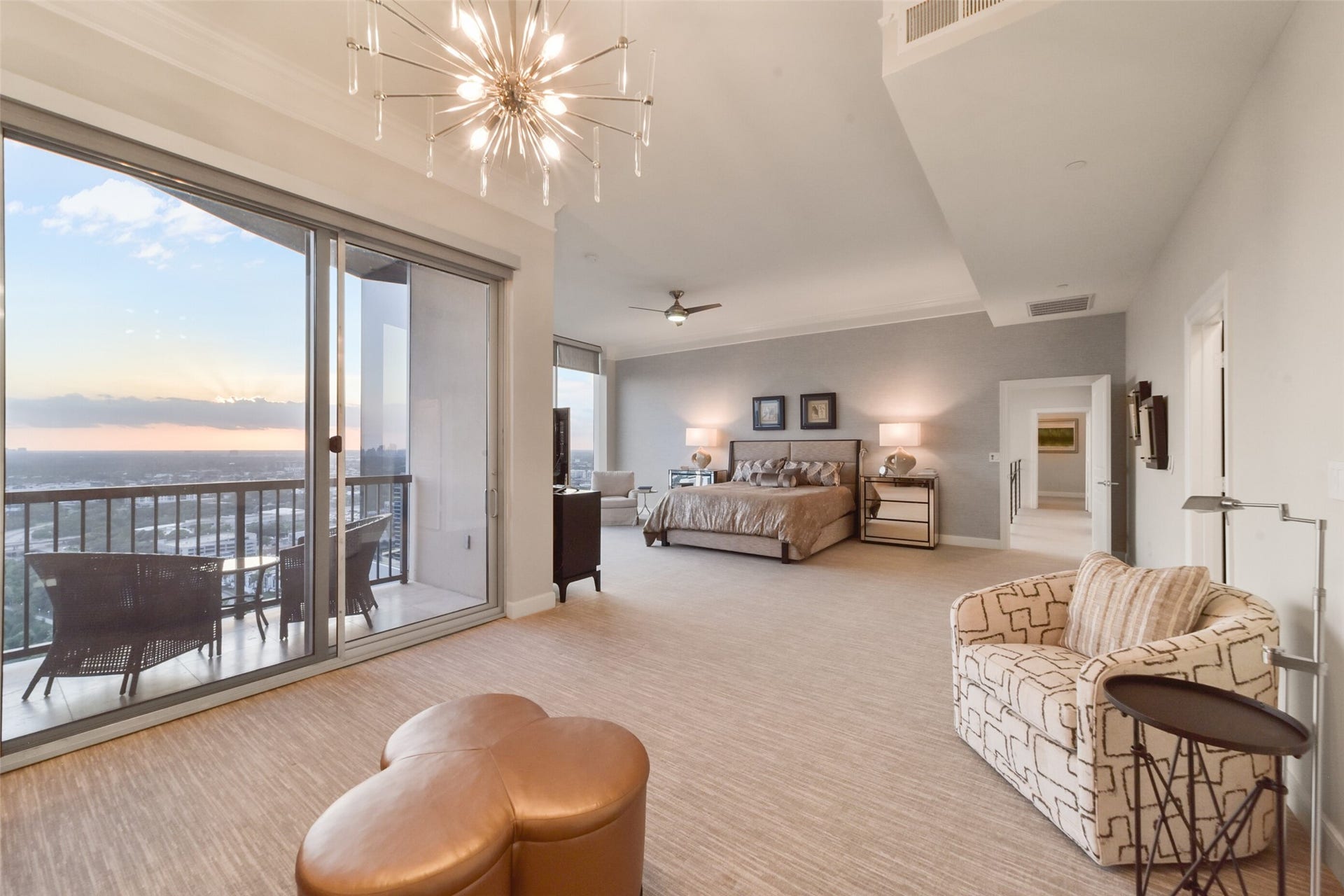 3333 Allen Parkway, #3003, Houston, TX 77019 Spacious, upstairs primary bedroom with modern lighting and plush carpeting, featuring large sliding doors that open to a private balcony with expansive views of the horizon. Two, separate, ensuite baths and closets are located off the right side of the bedroom.