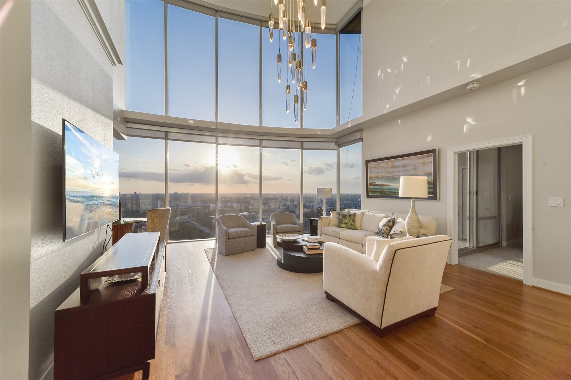 3333 Allen Parkway, #3003, Houston, TX 77019 Another view of the living room shows expansive western views over the tree tops of River Oaks and Buffalo Bayou, featuring an elegant chandelier. Ideal for those seeking an urban lifestyle with a touch of luxury.