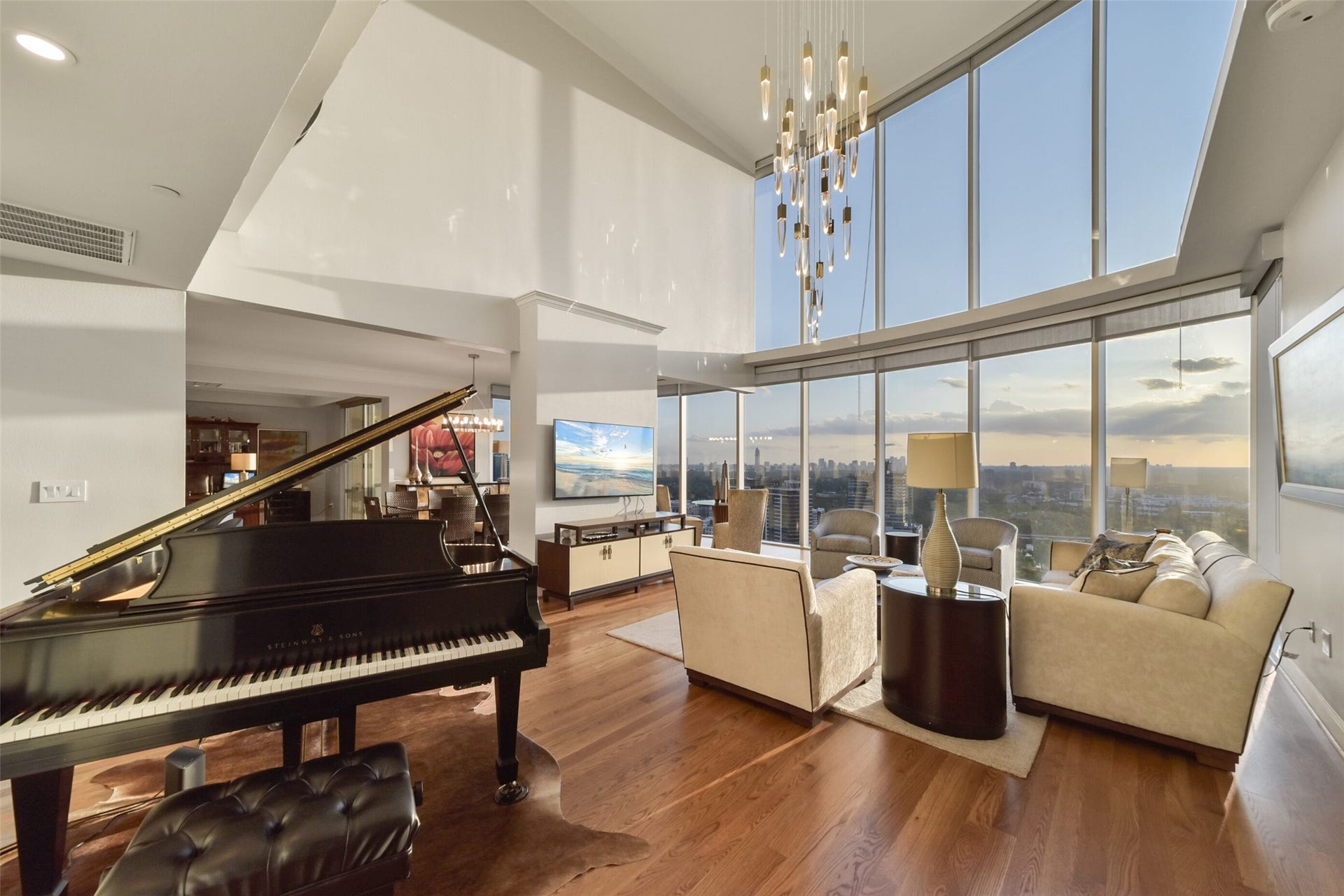 3333 Allen Parkway, #3003, Houston, TX 77019 Luxurious high-rise living space with two story floor-to-ceiling windows offering panoramic views, complemented by high ceilings, hardwood floors, and a grand piano, perfect for entertaining or relaxing in style.