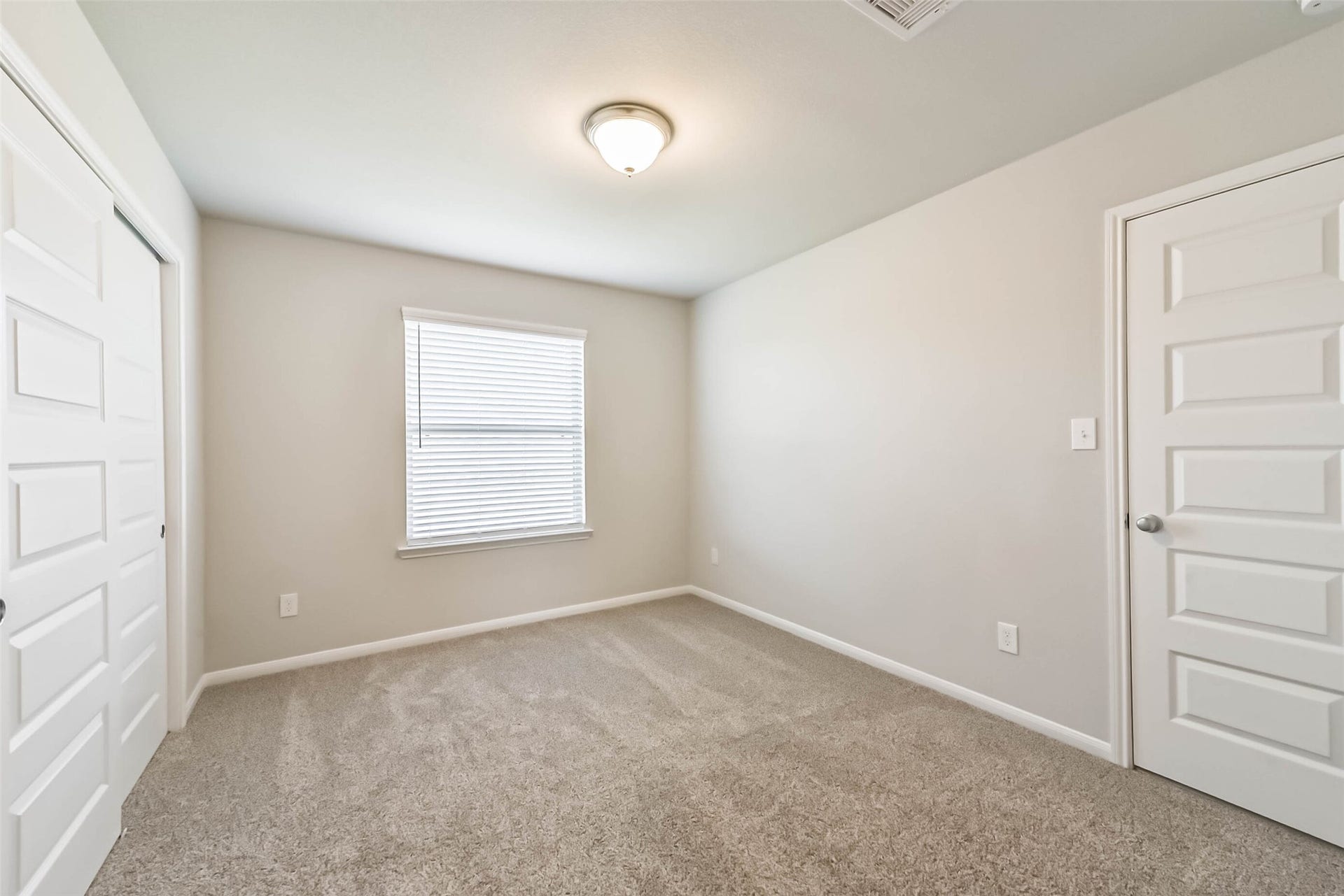 Light-filled bedroom with neutral carpeting.