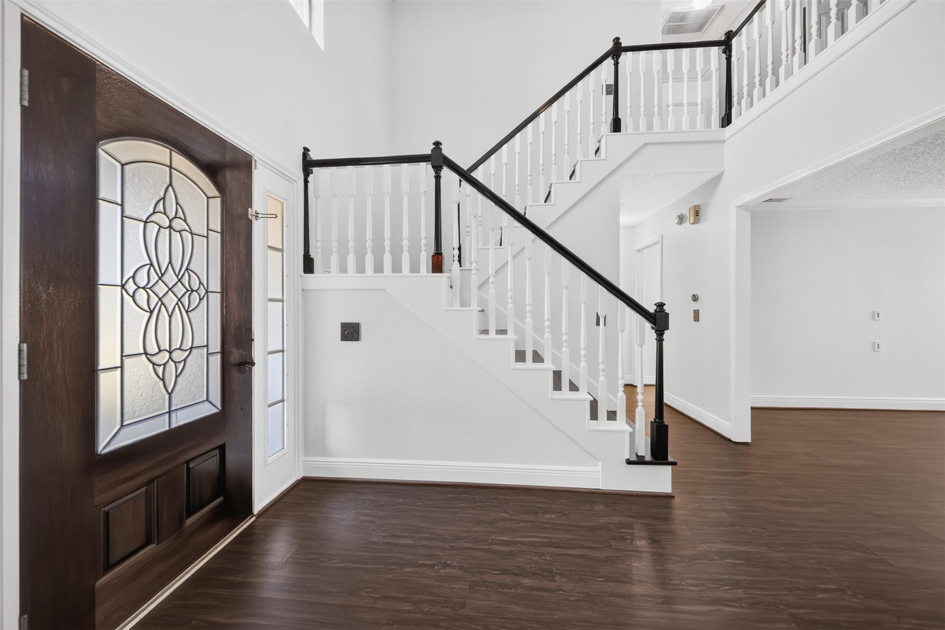 10215 Minturn Lane, Houston, TX 77064 Welcoming entryway featuring a beautiful front door, staircase with contrasting railings, and rich wood look flooring.