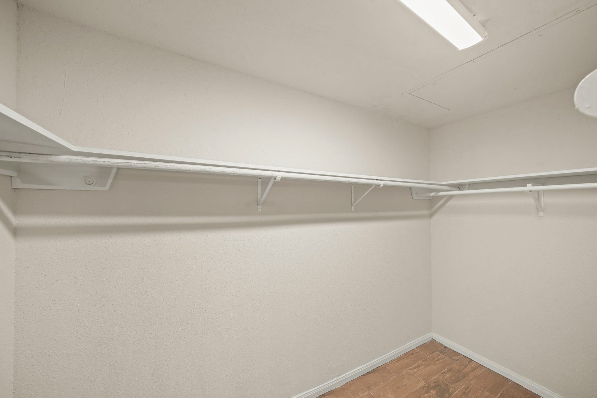 Spacious walk-in closet with white shelves and ample hanging space.