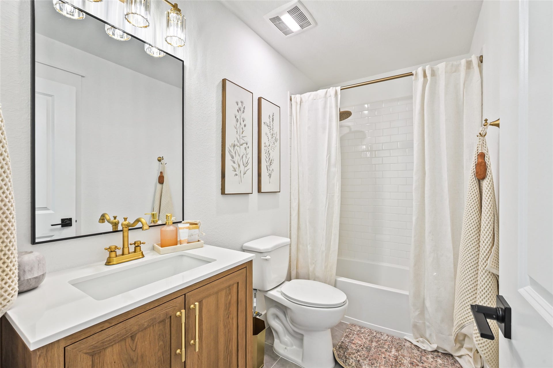 4121 Hazy Rock Lane, League City, TX 77573 gorgeous natural wood vanity with a sleek white countertop, an undermount sink, and elegant brushed-gold fixtures and cabinet hardware.
