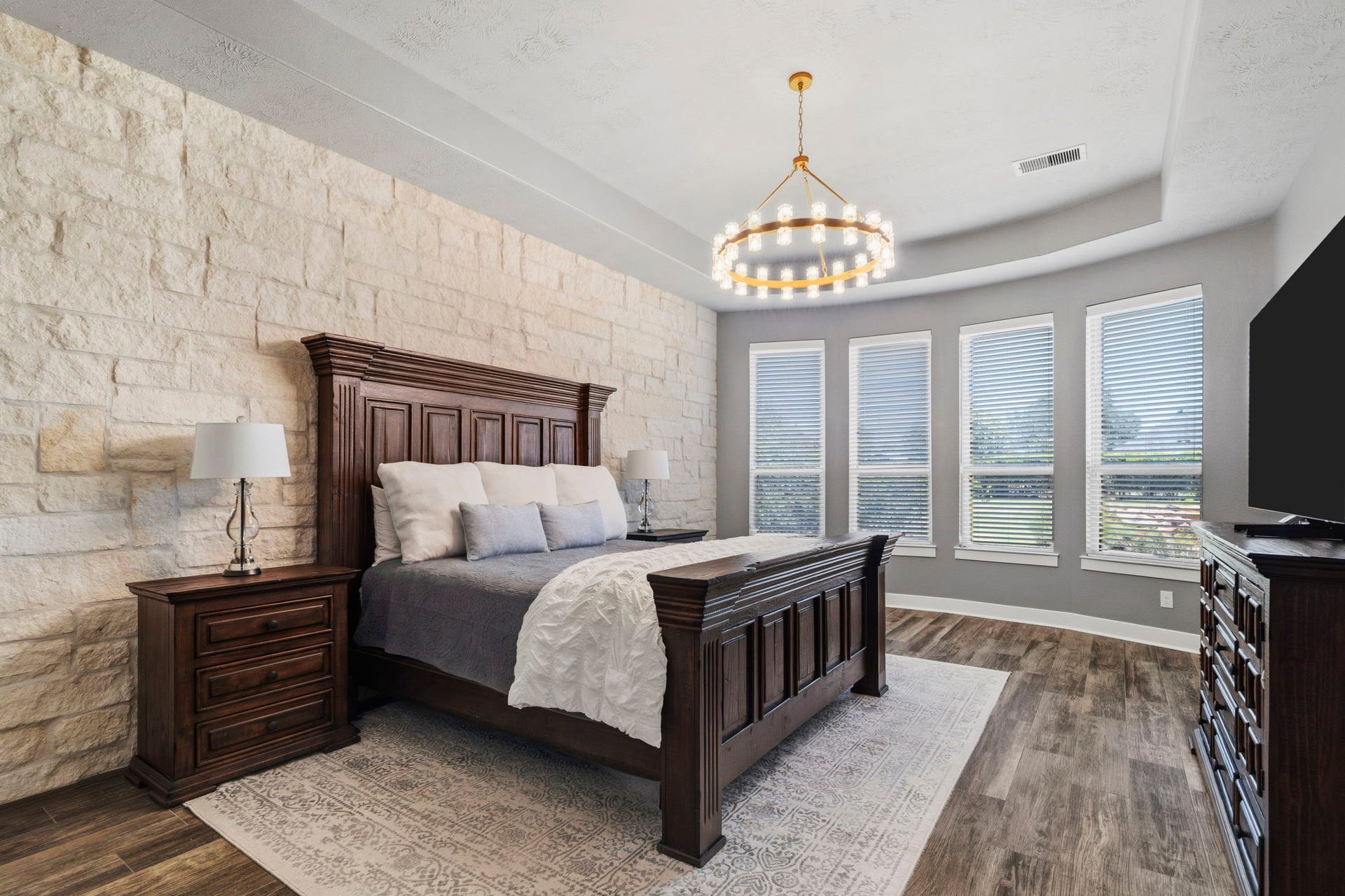 29826 Deer Crest Lane, Fulshear, TX 77406 The primary suite makes a statement with a dramatic stone accent wall, tray ceiling & designer lighting, while a series of windows brings in abundant natural light.