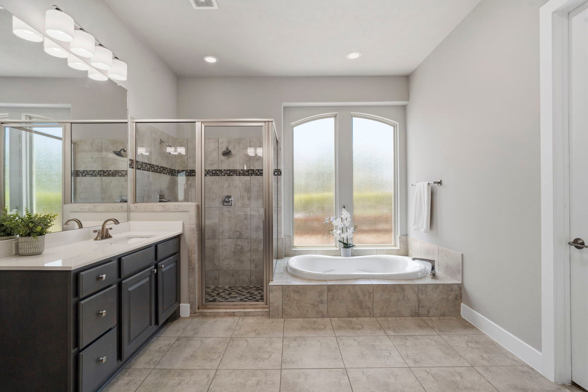 29826 Deer Crest Lane, Fulshear, TX 77406 The primary bath features a jetted soaking tub positioned beneath arched windows, a separate walk-in shower & dual vanities for a spacious, functional layout.
