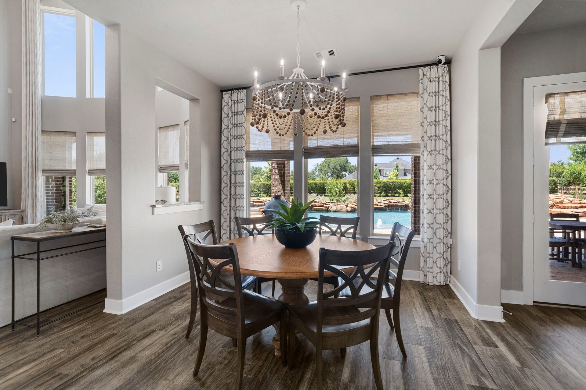 29826 Deer Crest Lane, Fulshear, TX 77406 The breakfast room is framed by backyard views and features custom draperies & Roman shades, complemented by a statement designer light fixture