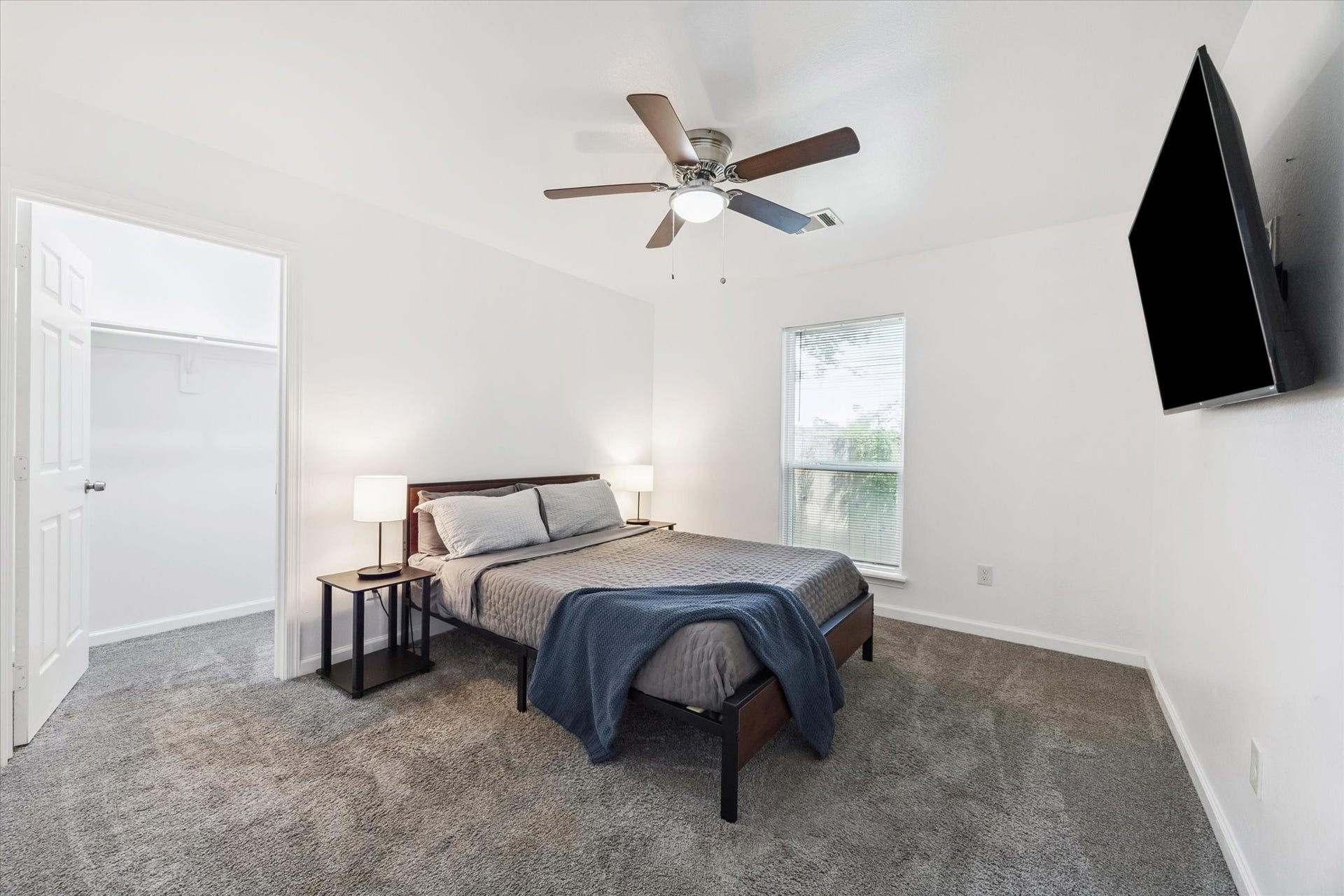 2631 Stevens Street, Houston, TX 77026 This secondary bedroom features a spacious walk-in closet, a large window that brings in natural light, and a ceiling fan with a light kit for added comfort. Plush carpeting and neutral finishes make it move-in ready.