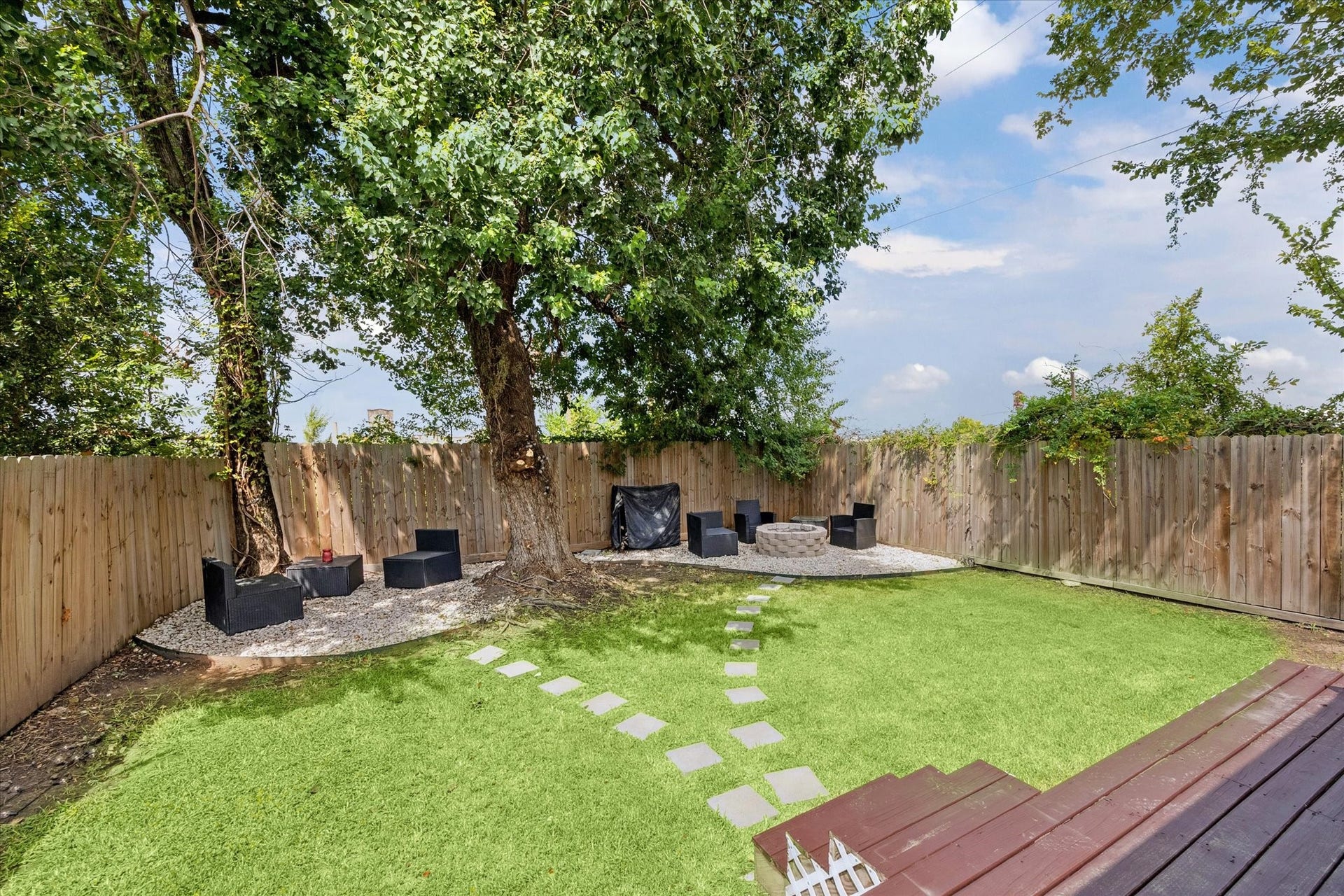 2631 Stevens Street, Houston, TX 77026 Mature shade trees frame a private backyard retreat with multiple seating areas, including a firepit corner perfect for evening gatherings. The fully fenced yard combines green space with low-maintenance gravel accents for easy enjoyment.