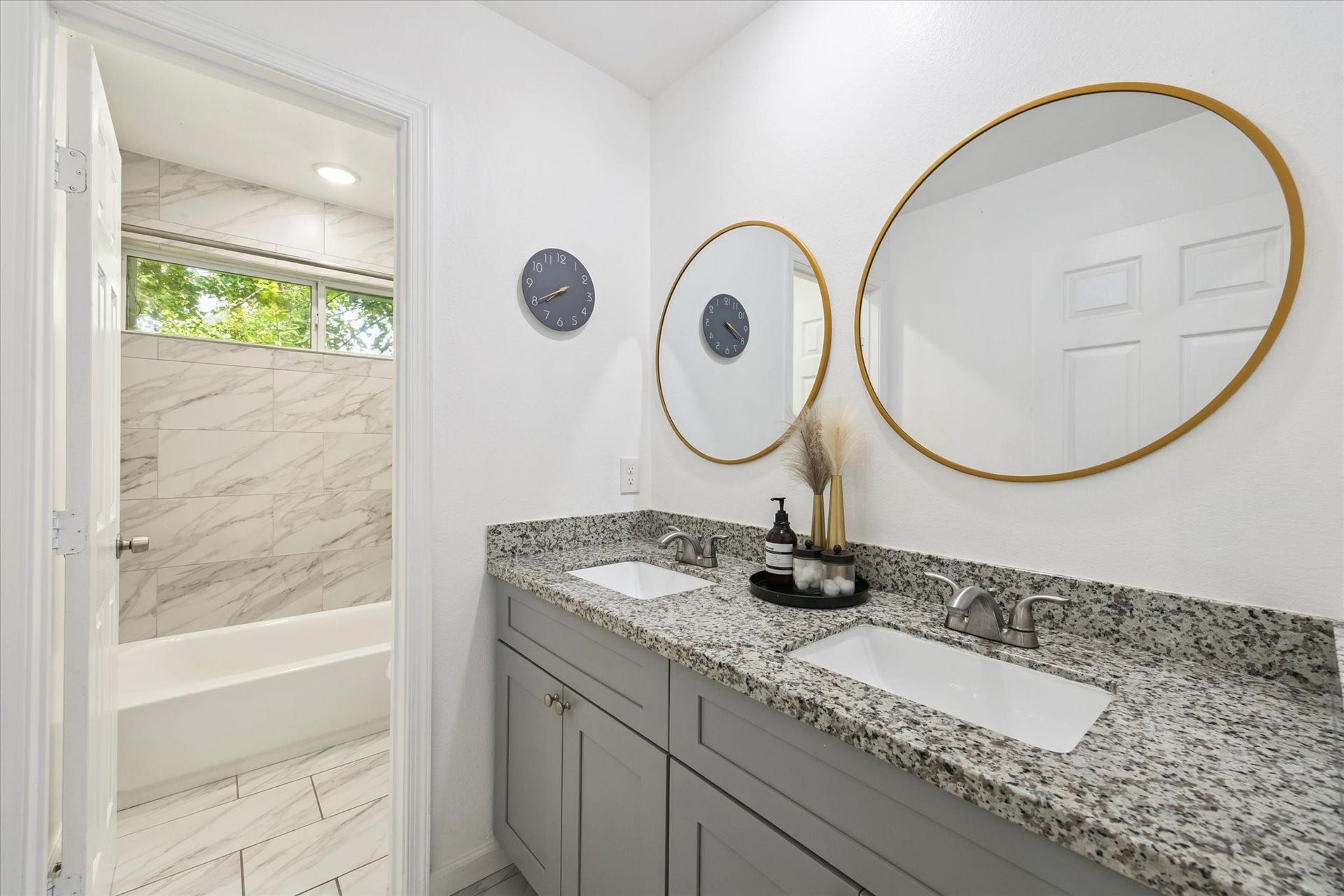 2631 Stevens Street, Houston, TX 77026 The secondary bathroom is designed for convenience with dual sinks, granite counters, and framed mirrors. A separate space for the tub and shower provides privacy and functionality for shared use.