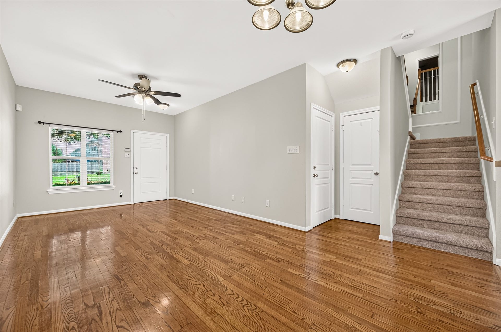 Abundant natural light streams through the energy-efficient double-pane windows installed in 2024, highlighting the rich wood flooring, while BRAND-NEW premium-grade carpet and padding add a fresh touch to the staircase.