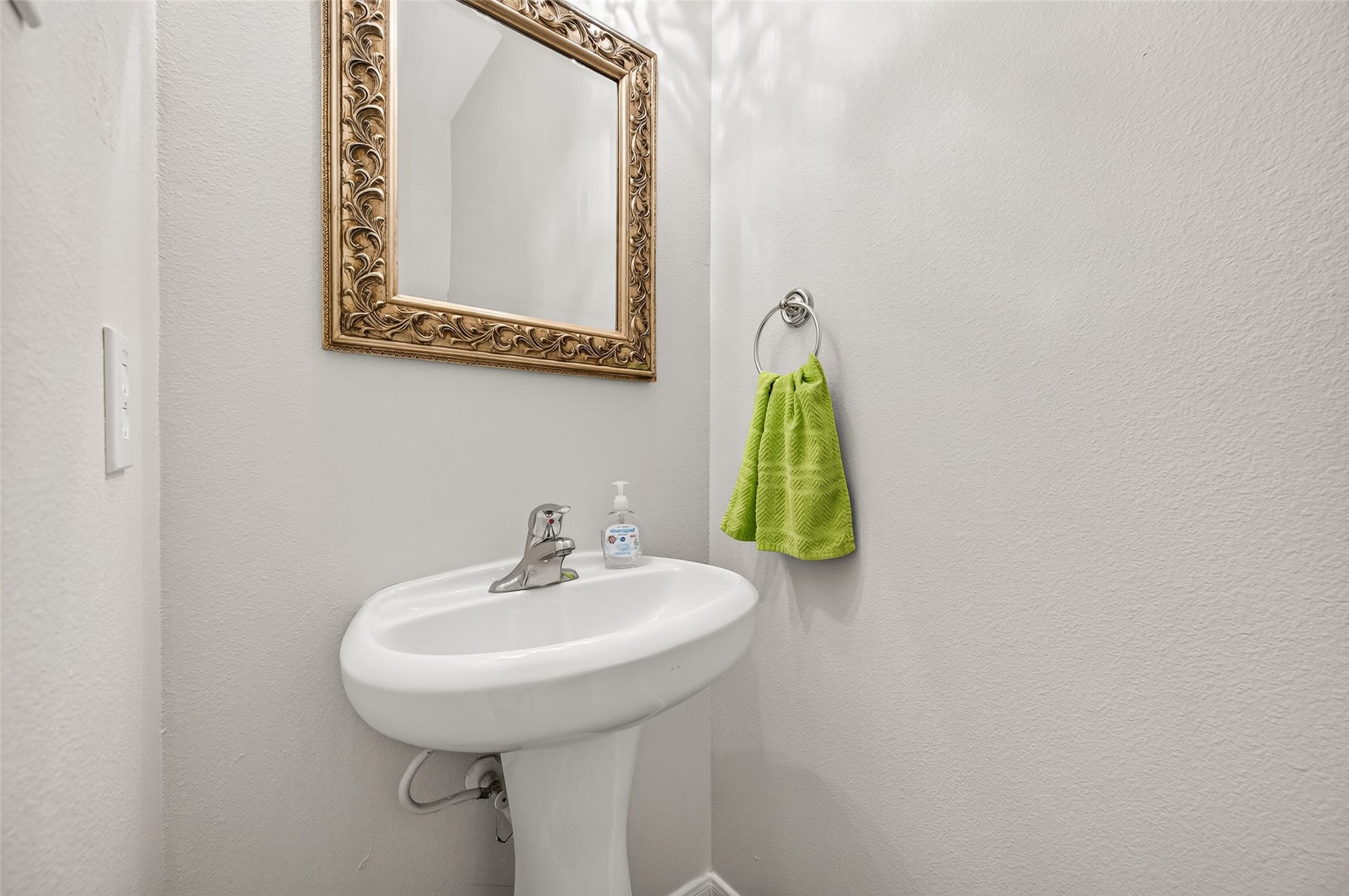 This convenient main-level half bath features a classic pedestal sink, sleek chrome fixtures, and a stylish ornate mirror.