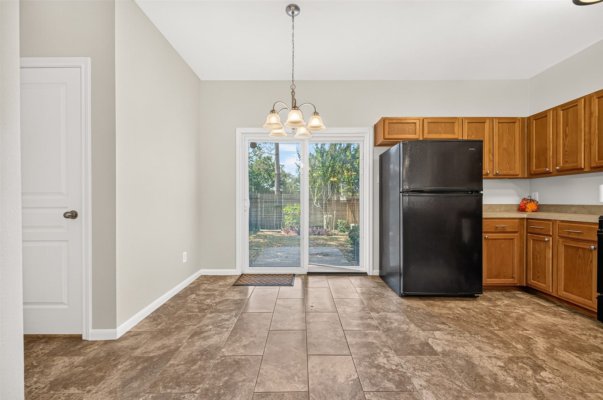 This bright breakfast area features tile flooring installed in 2023 and a sliding glass door added in 2018 with convenient built-in blinds and relaxing backyard views.