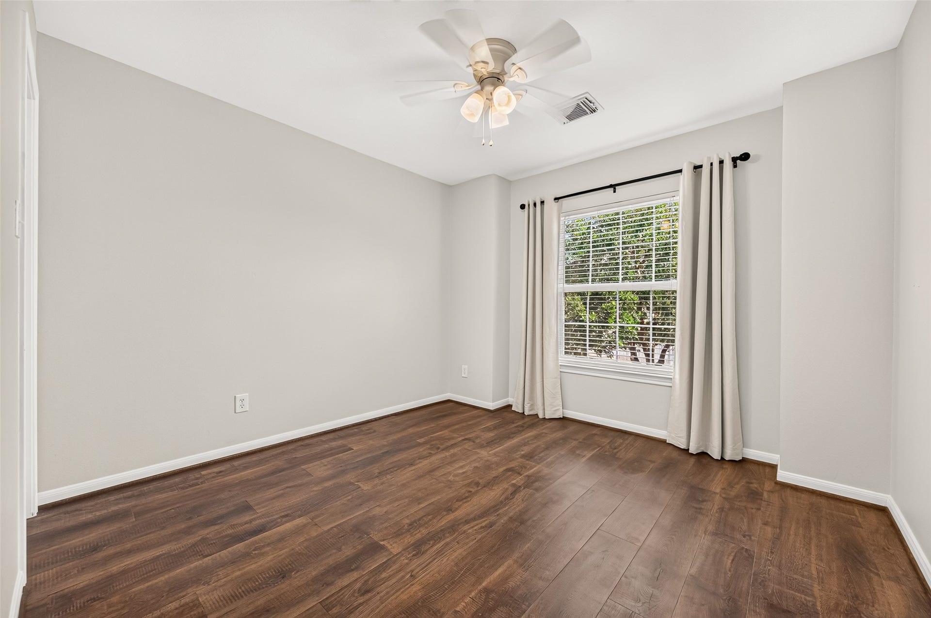 Bright and inviting guest bedroom featuring a large window for abundant natural light and a soothing ceiling fan for added comfort.
