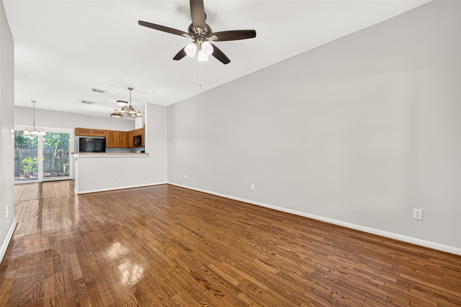 This open-concept living area with HARDWOOD FLOORING flows seamlessly into the kitchen and dining space and features walls, ceilings, and trim repainted in 2023, plus an updated HVAC heating component and thermostat (2024).