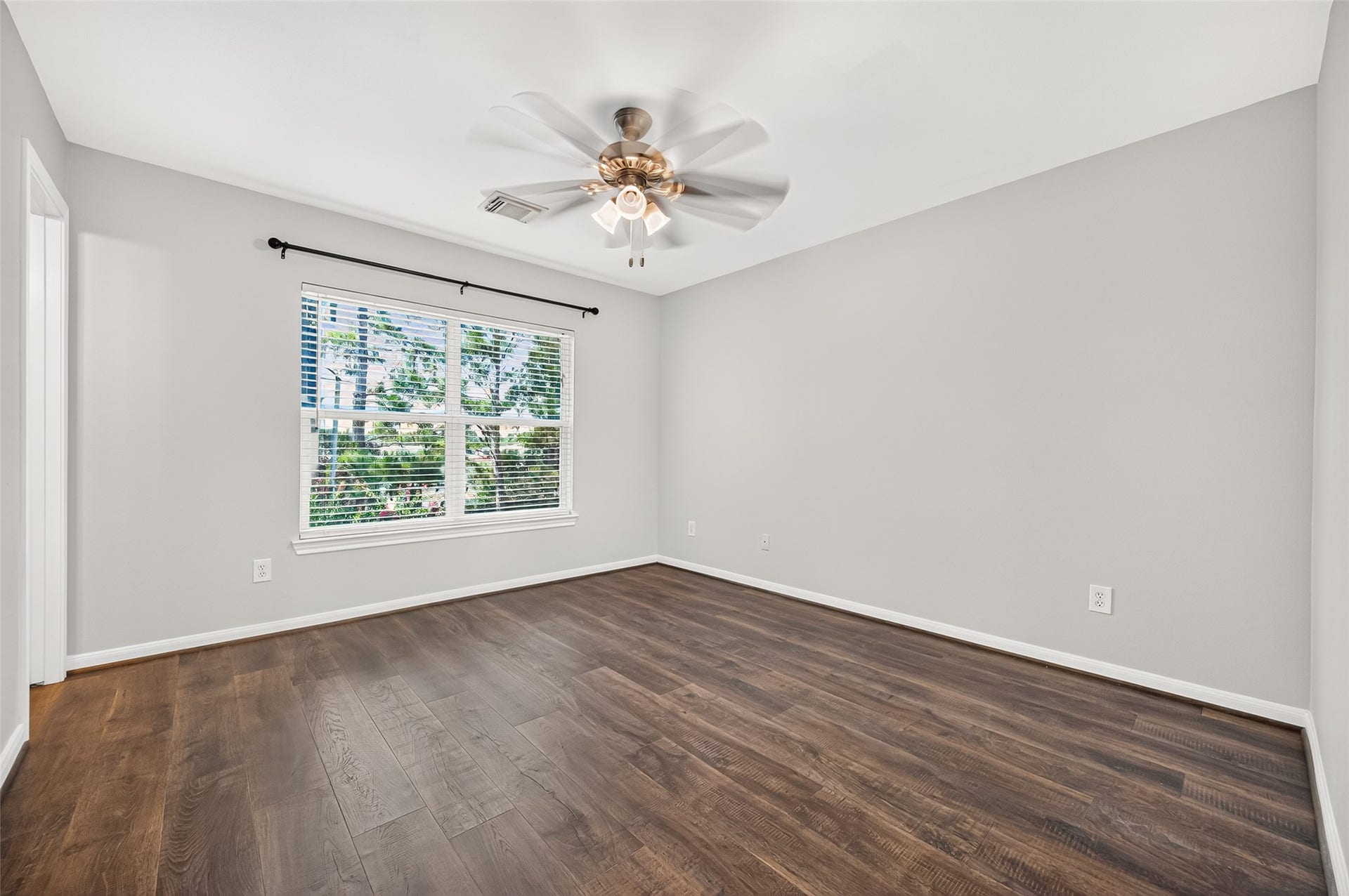 The peaceful primary bedroom features neutral paint, a large window for natural light, and a soothing ceiling fan for year-round comfort.