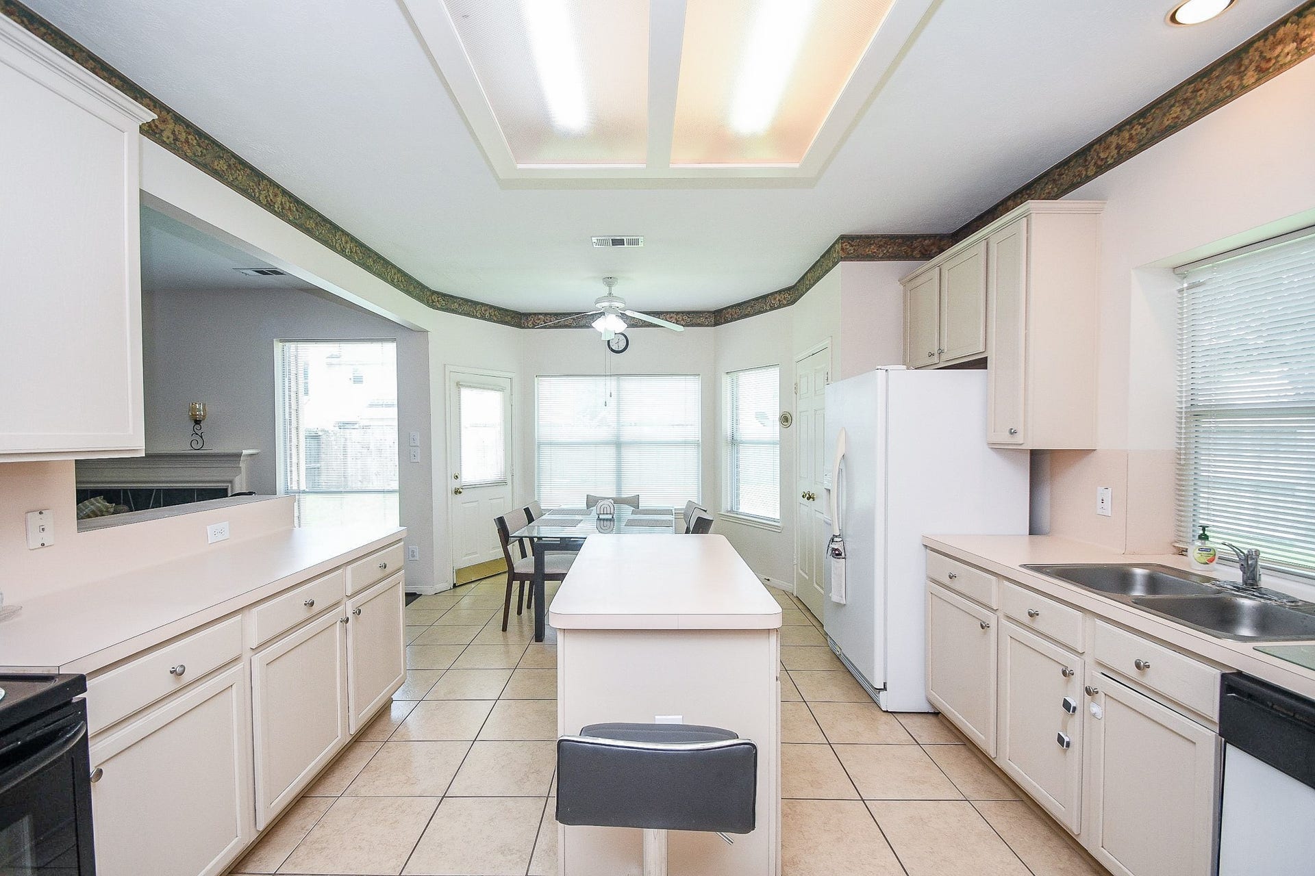15715 Brookwood Lake Place, Sugar Land, TX 77498 Bright and spacious kitchen with ample cabinetry, a central island, and tile flooring. It features a breakfast area with large windows for natural light, and a ceiling fan for comfort.