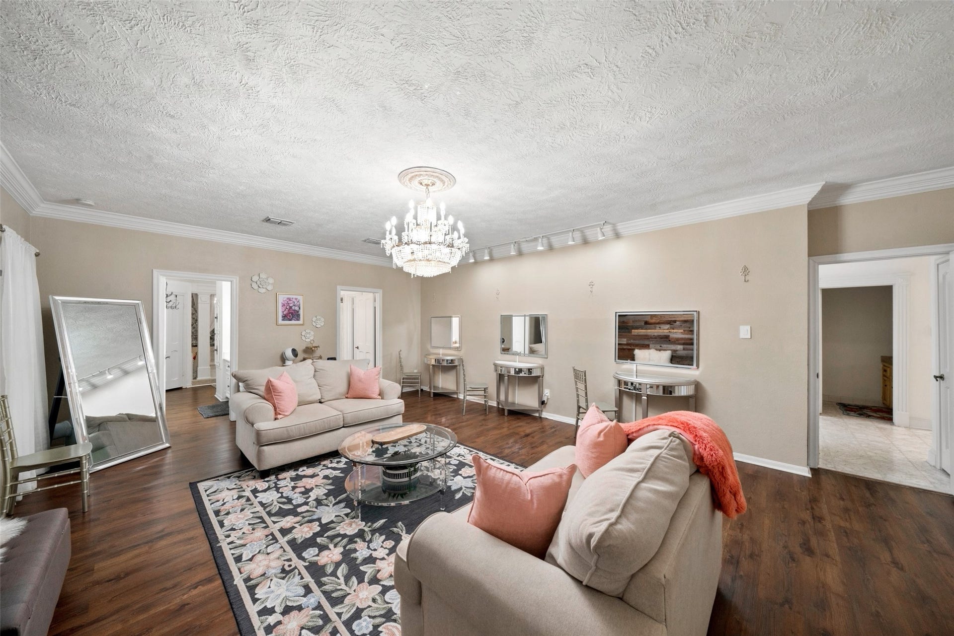 Spacious room currently used as a bridesmaids getting-ready lounge, with potential for use as a primary bedroom. Features include wood flooring and a chandelier.